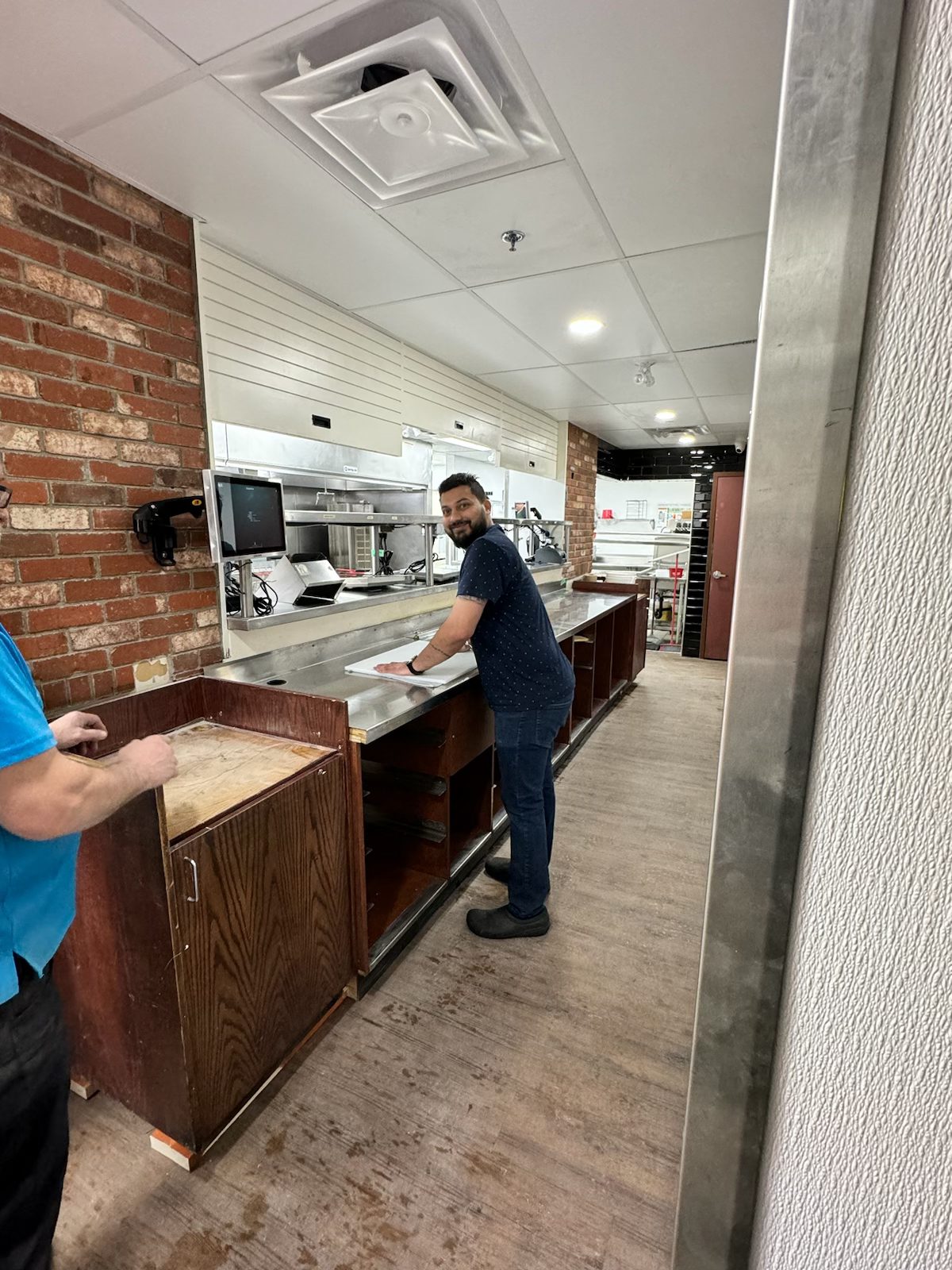 Workers install stainless steel counters in unfinished commercial kitchen — Blowers and Grafton (Medicine Hat)