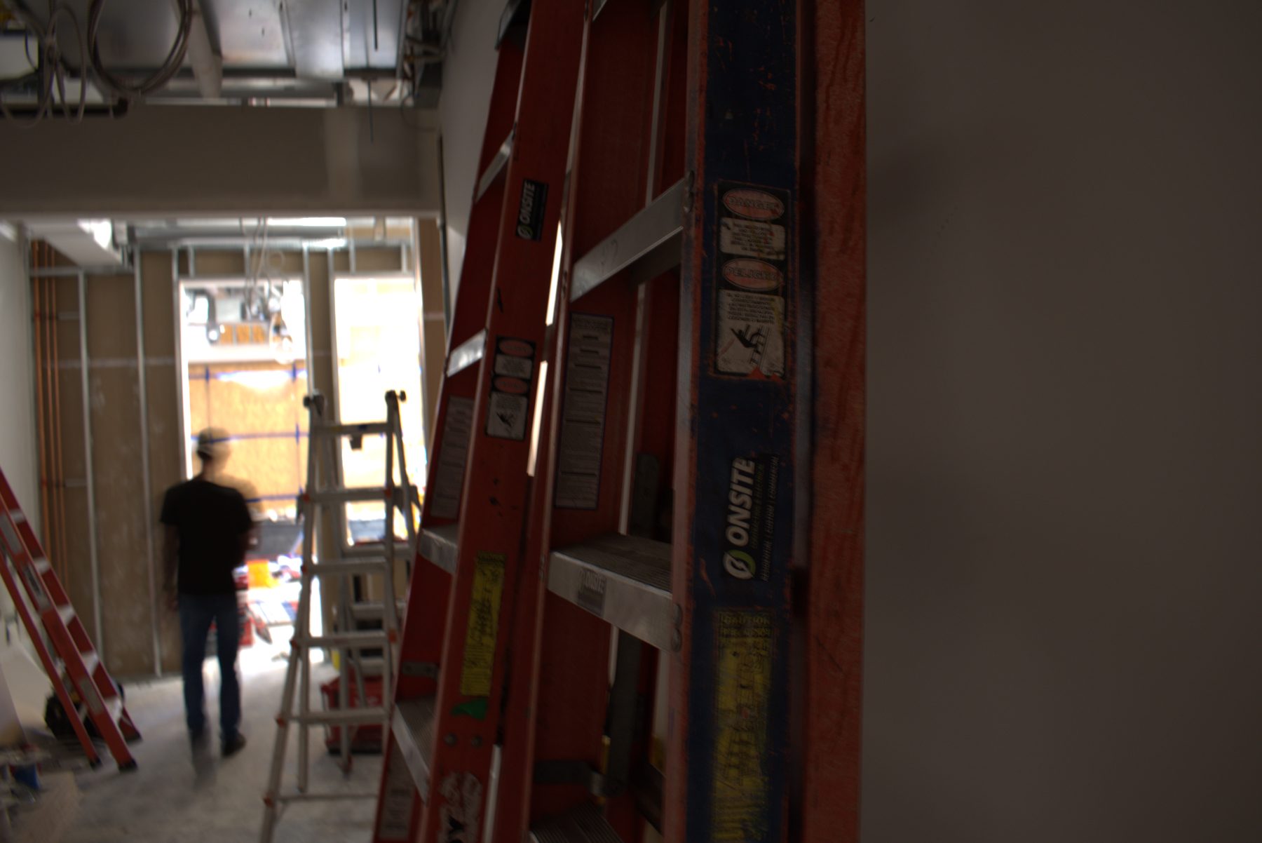 Construction site with ladders and a person working on framing — Big Buns (Bowness)