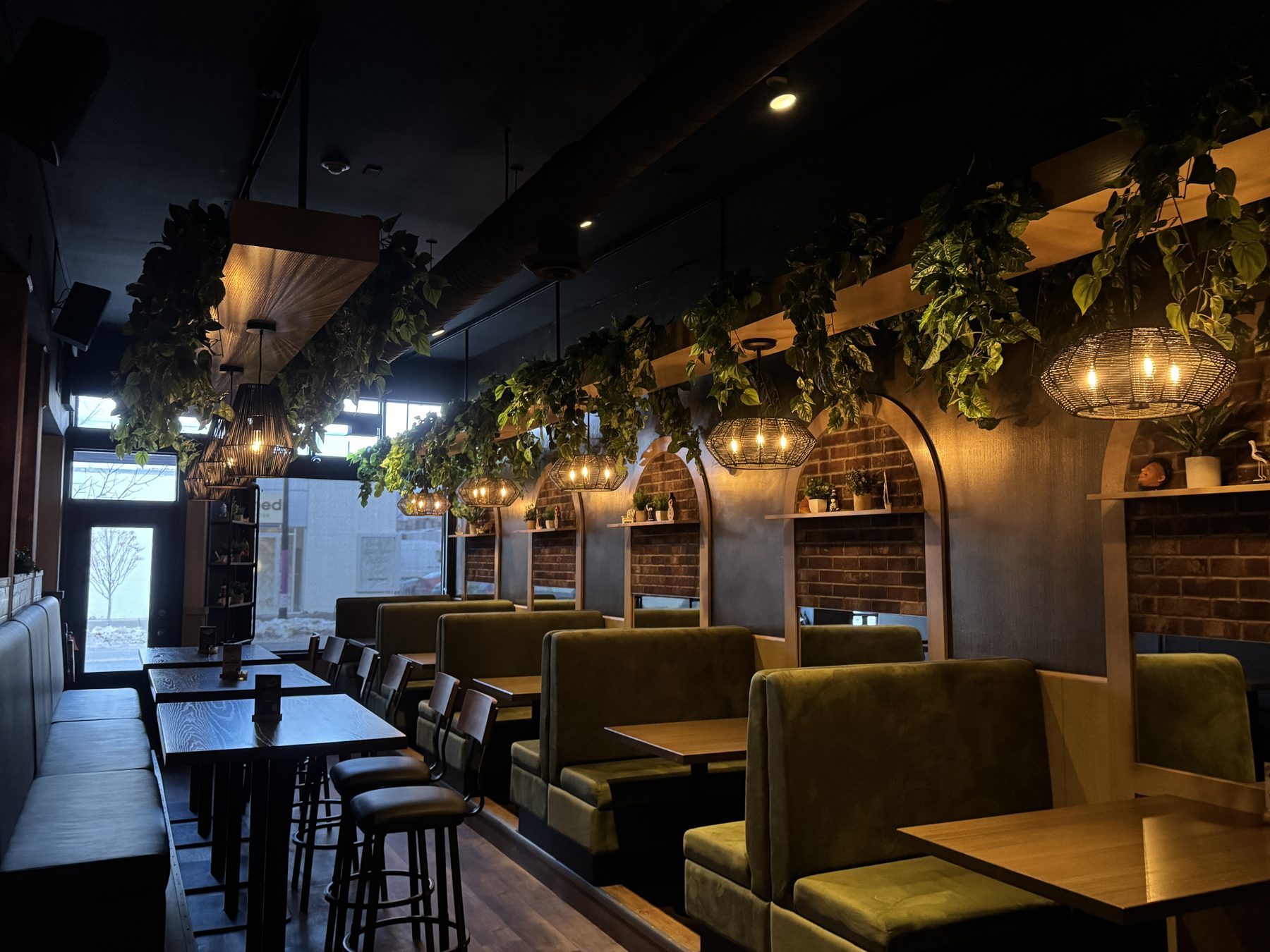 Restaurant dining area with green booths, wood tables, and hanging plants — Blowers and Grafton (Mission)