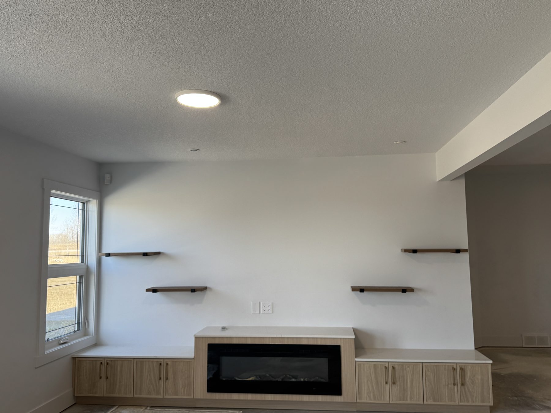 Living room with fireplace, shelving, and a window — 14 Lochend Drive, Cochrane