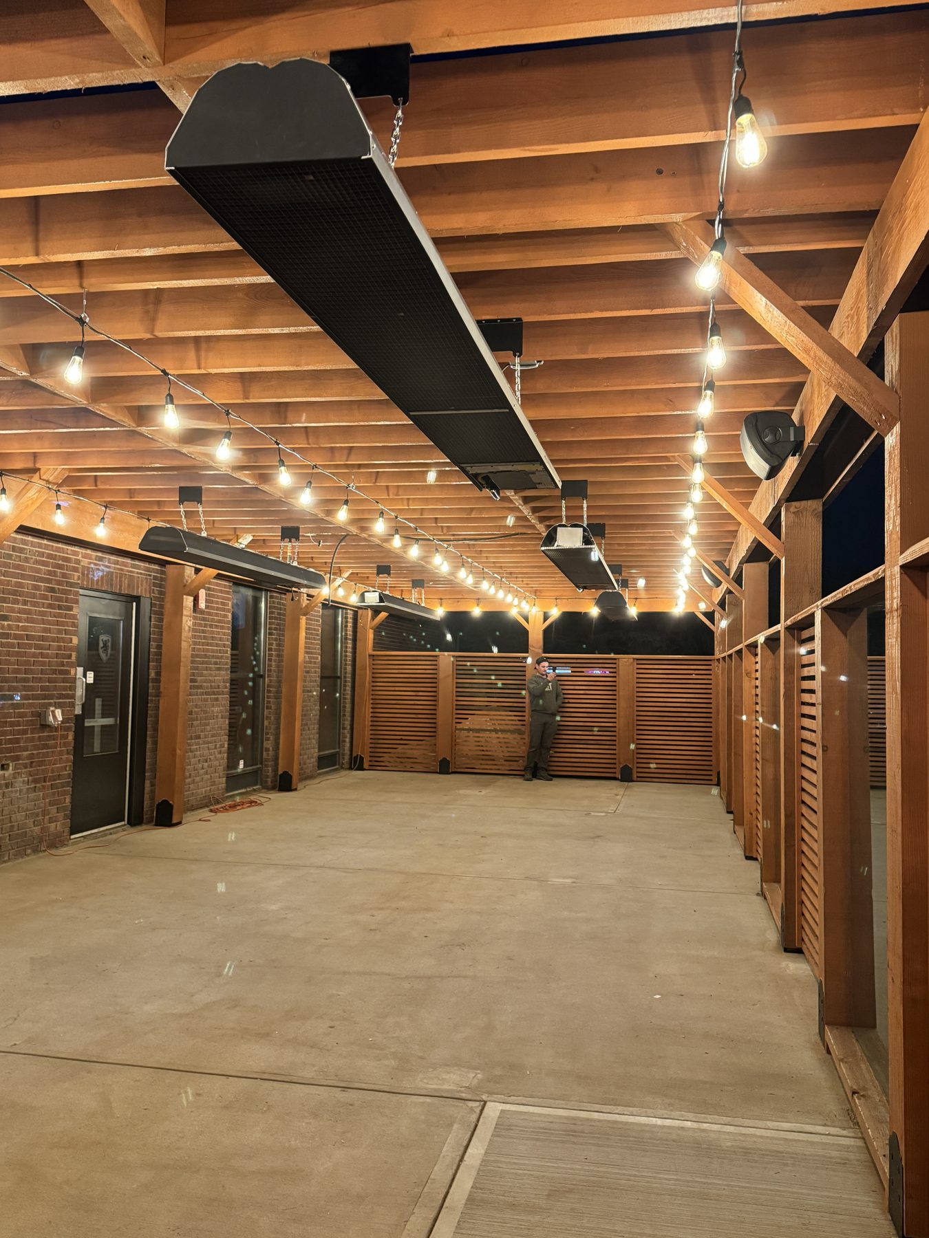Outdoor patio under construction with heaters, string lights, and wood screening — Blowers and Grafton (Medicine Hat)