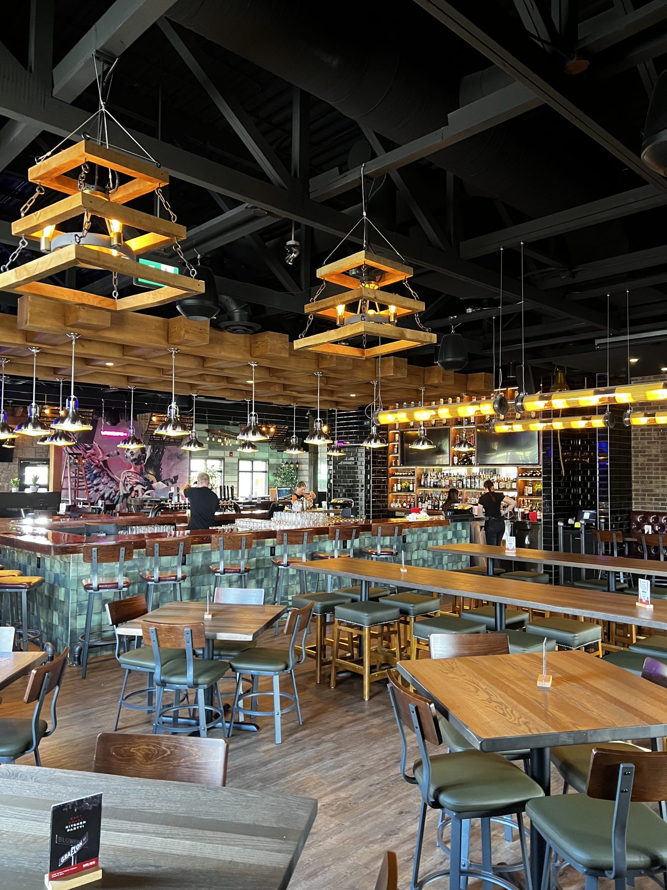 Restaurant bar with wood accents, green tile, and industrial lighting fixtures — Blowers and Grafton (Lethbridge)