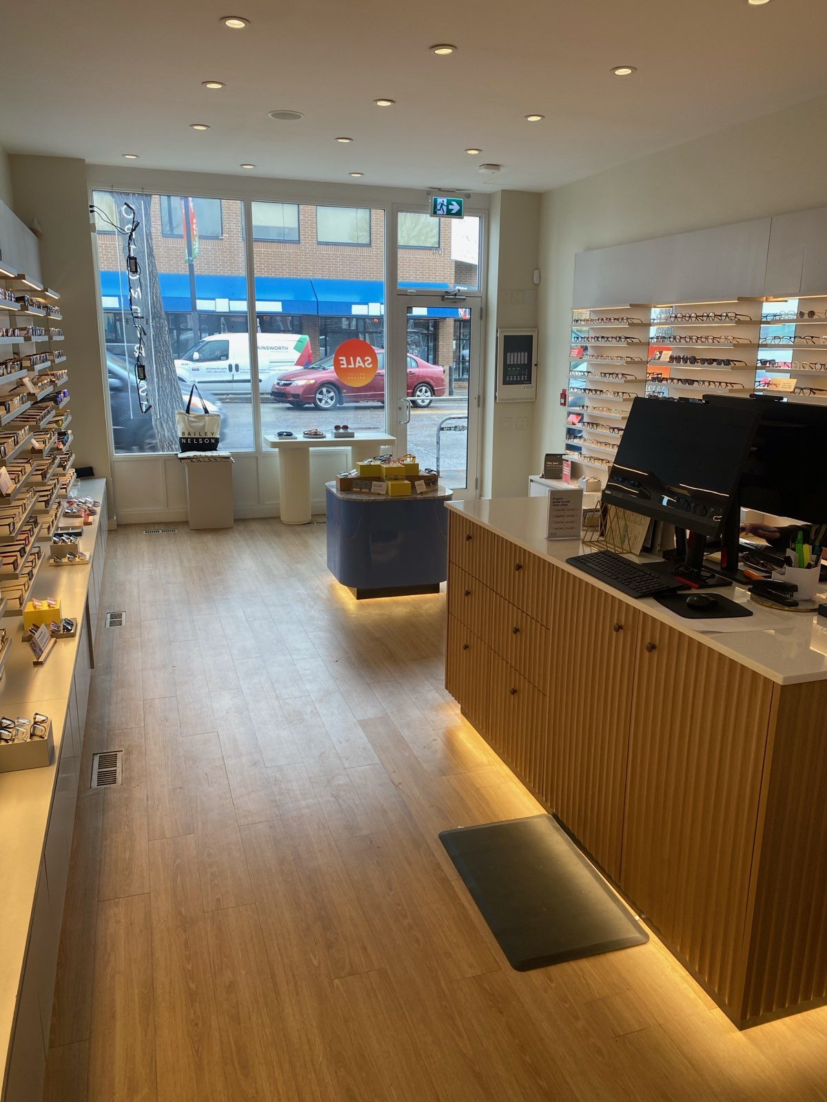 Modern optical shop interior with slat wood counter and eyewear displays — 104 10 Street Northwest, Calgary (Bailey Nelson)