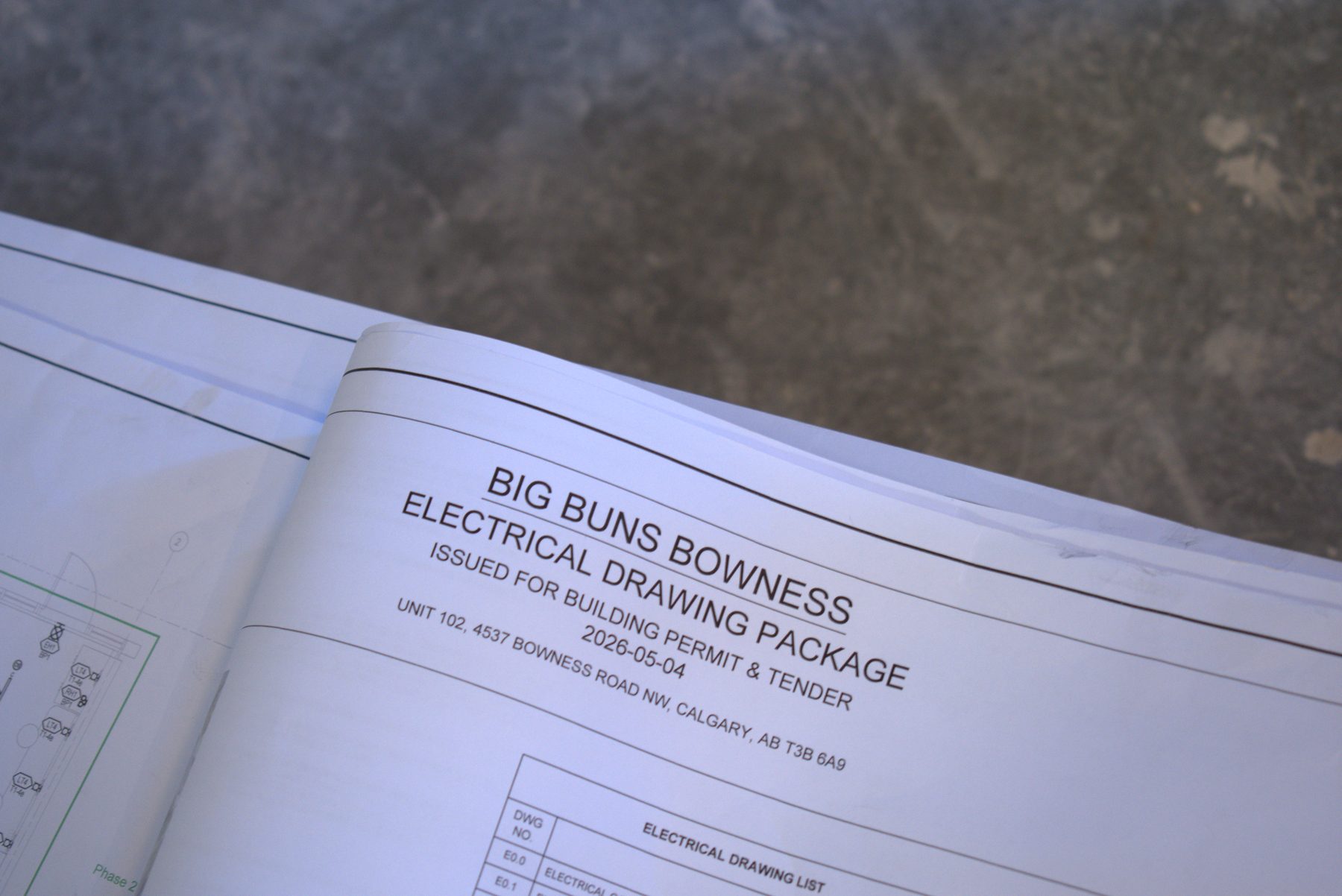 Construction plans on concrete surface with electrical drawing package details — Big Buns (Bowness)