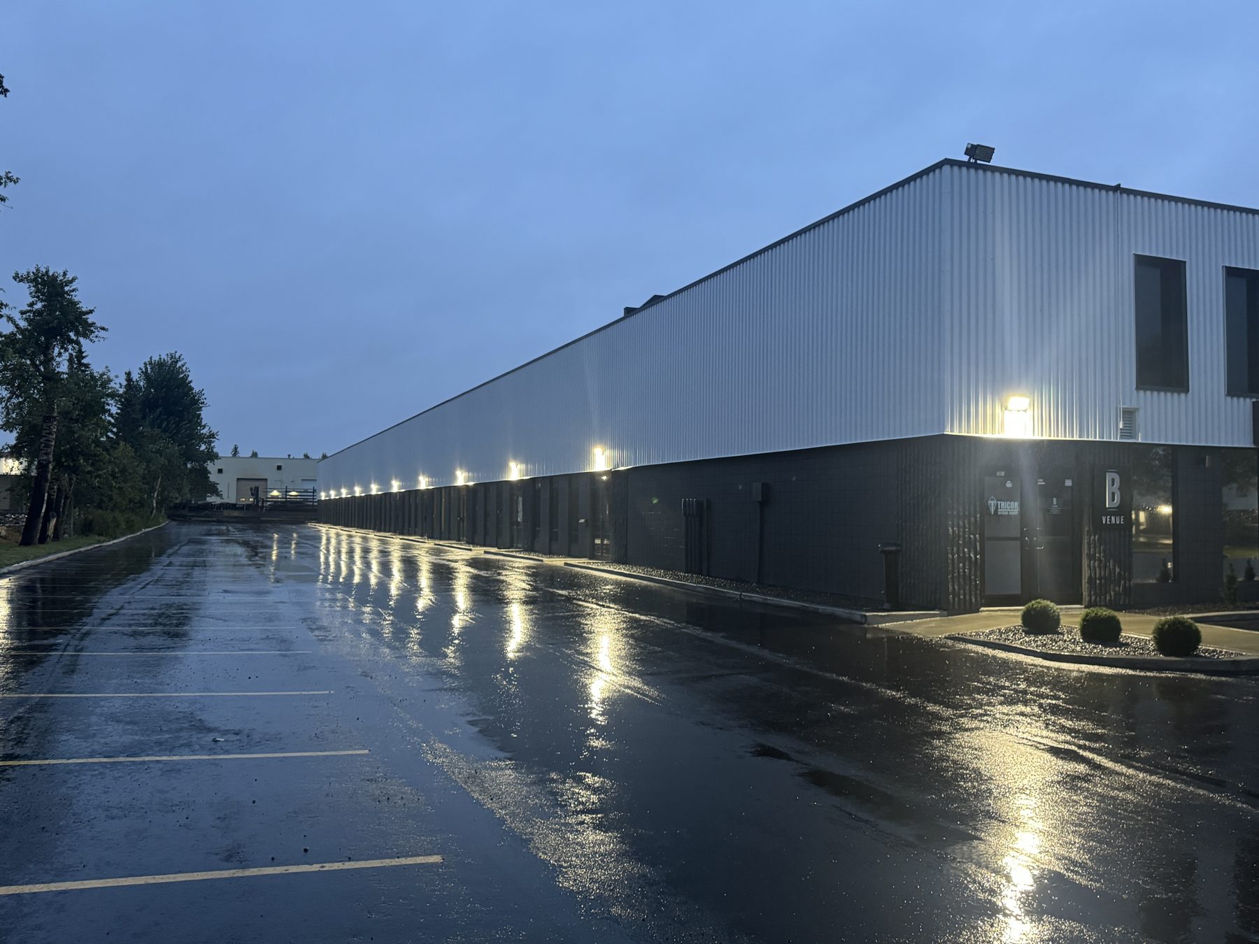 Modern warehouse exterior with corrugated metal siding and dark brick base — The Barron Venue