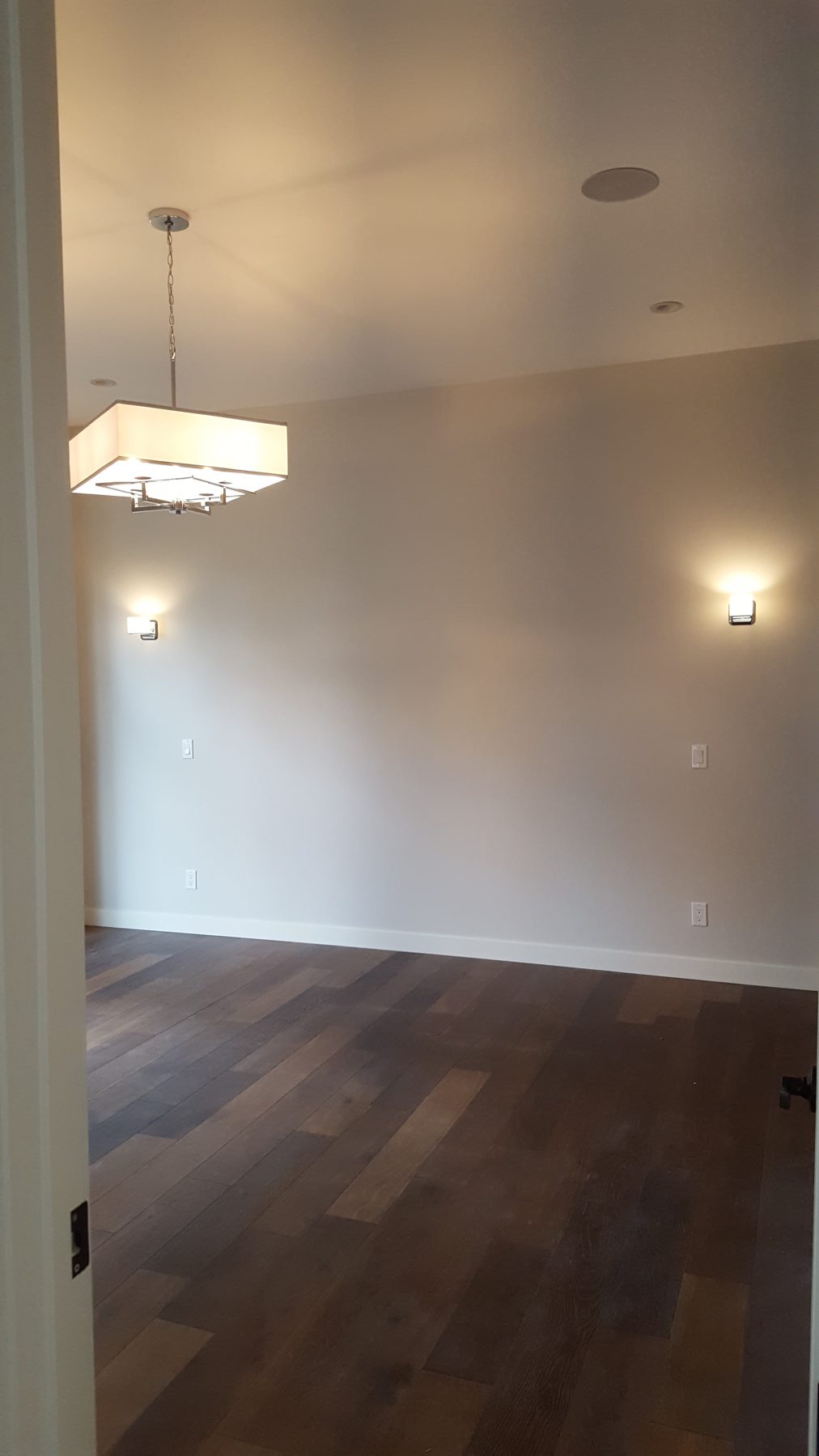 Room with dark wood floor, modern chandelier, and wall sconces — Briar Hill