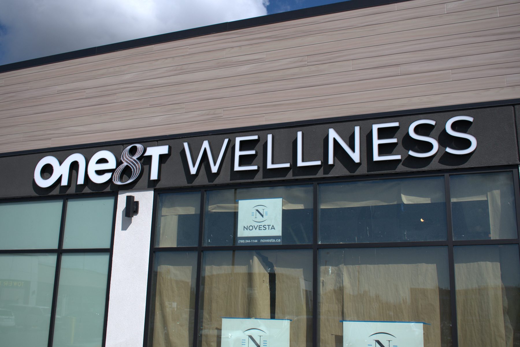 Business storefront with illuminated signage and window displays — ONE8T (West District)