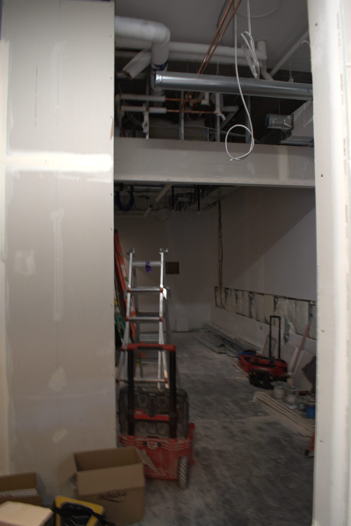 Construction in progress with exposed pipes, drywall, and ladder — Big Buns (Bowness)