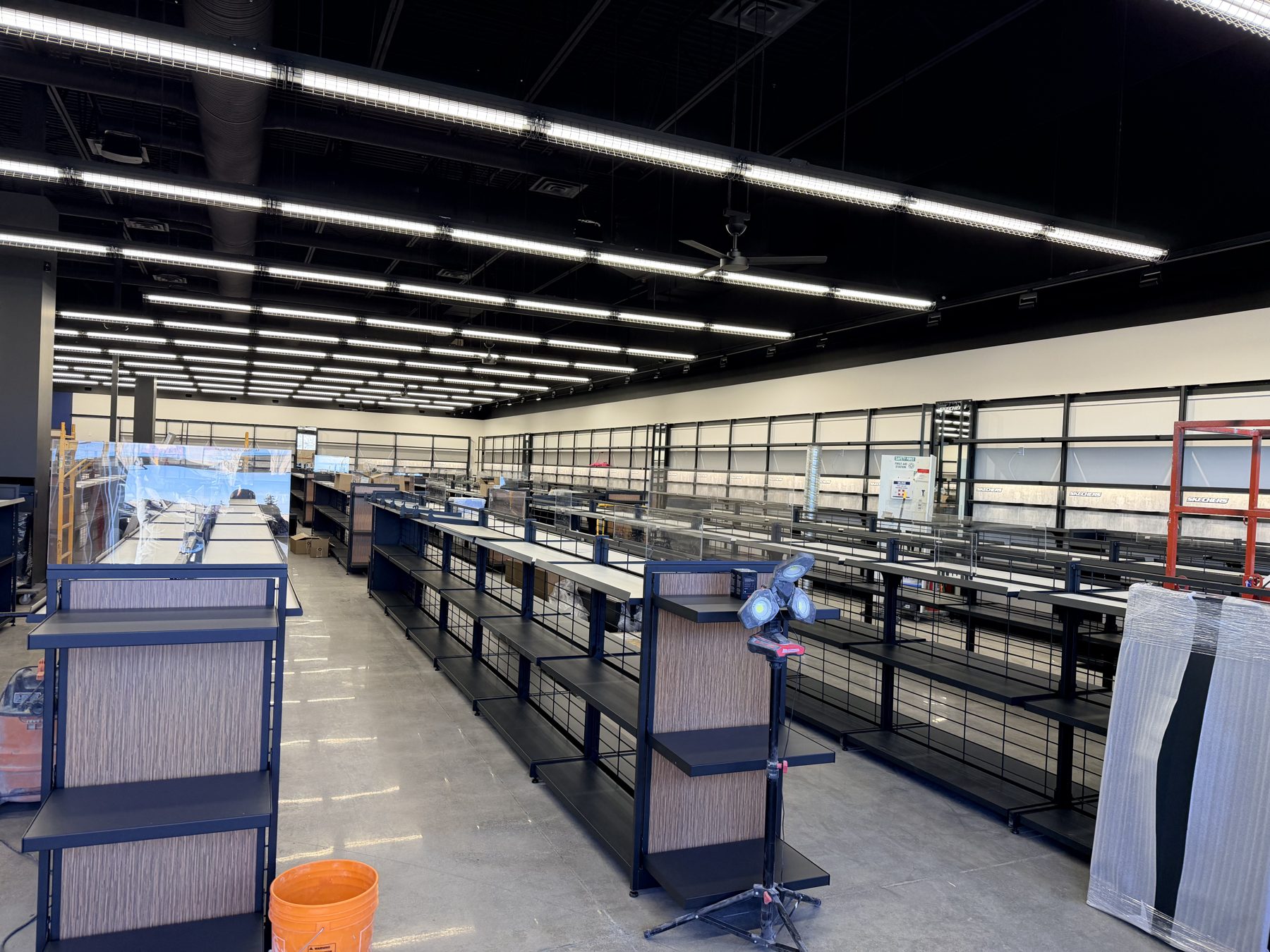 Store interior construction with empty shelves and new lighting installed — Skechers (Signal Hill) by Onsite Contracting Services