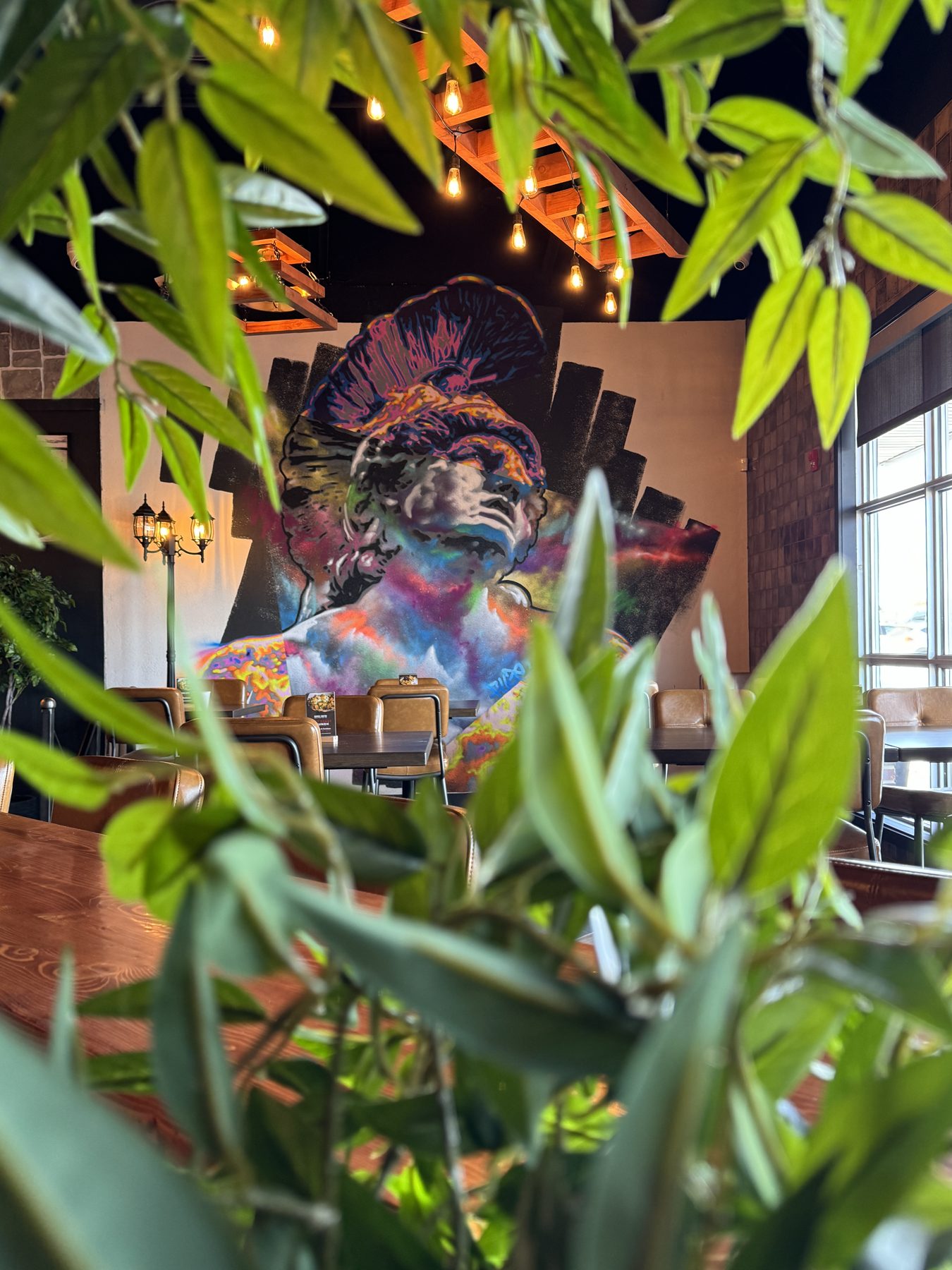Restaurant dining area with mural, wooden tables, leather chairs, and industrial lighting — Blowers and Grafton (Medicine Hat)