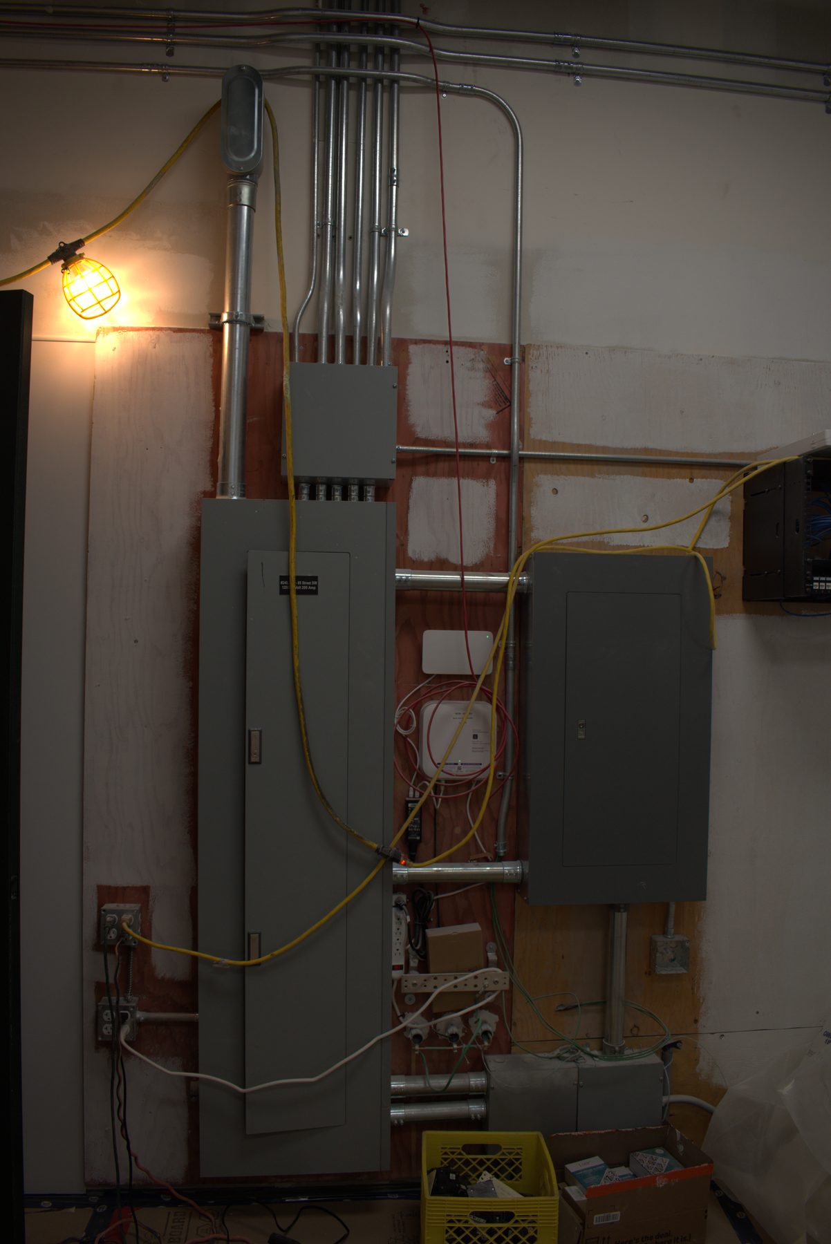 Electrical panel installation with conduit, wiring, and temporary lighting — ONE8T (West District)