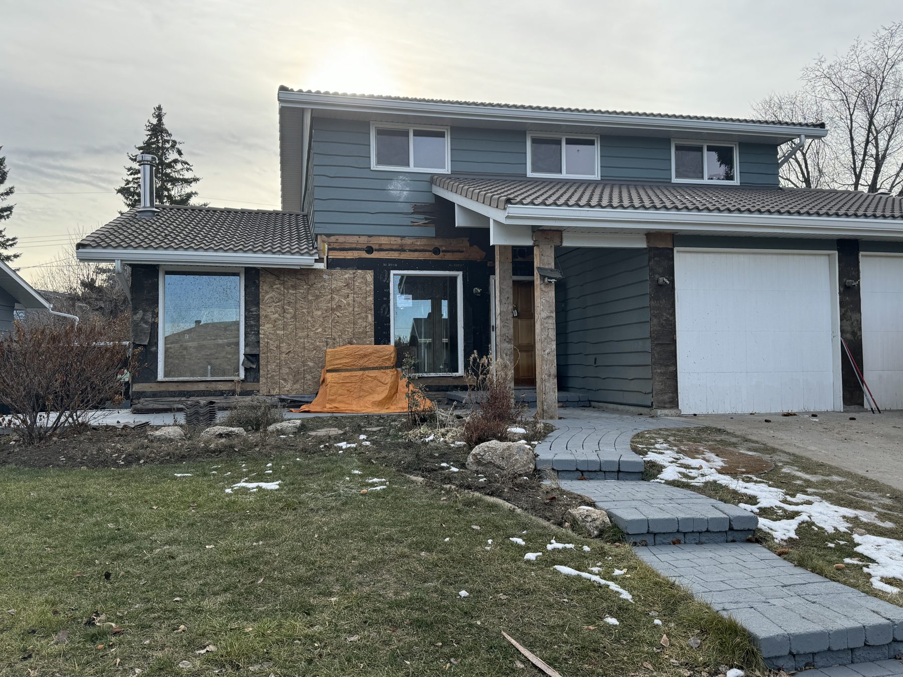 House exterior under renovation, exposed plywood and orange tarp — 188 Lake Adams Crescent SE, Calgary by Onsite Contracting Services