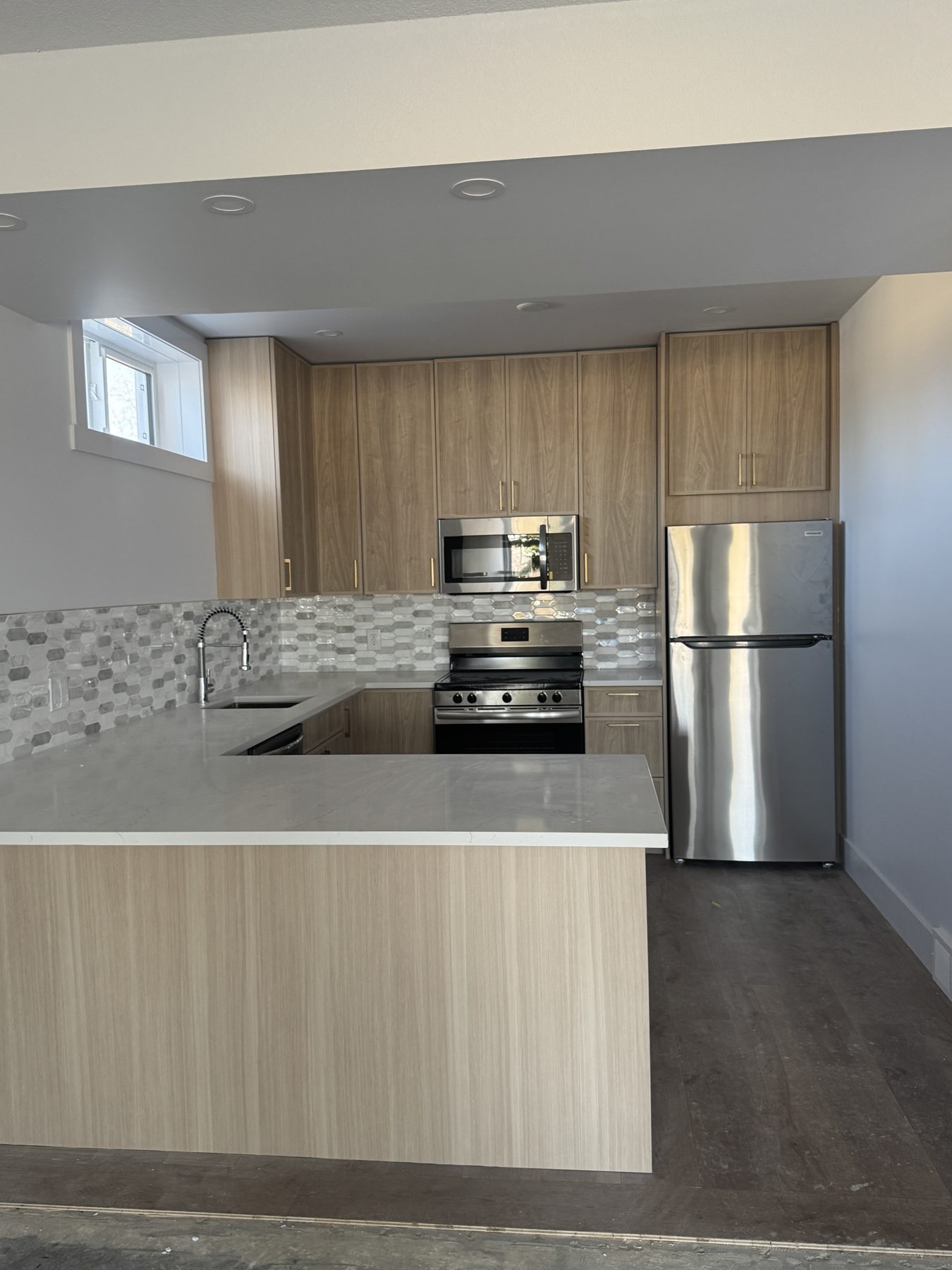 Newly renovated kitchen with light wood cabinets, stainless steel appliances, and marble countertops — 14 Lochend Drive, Cochrane
