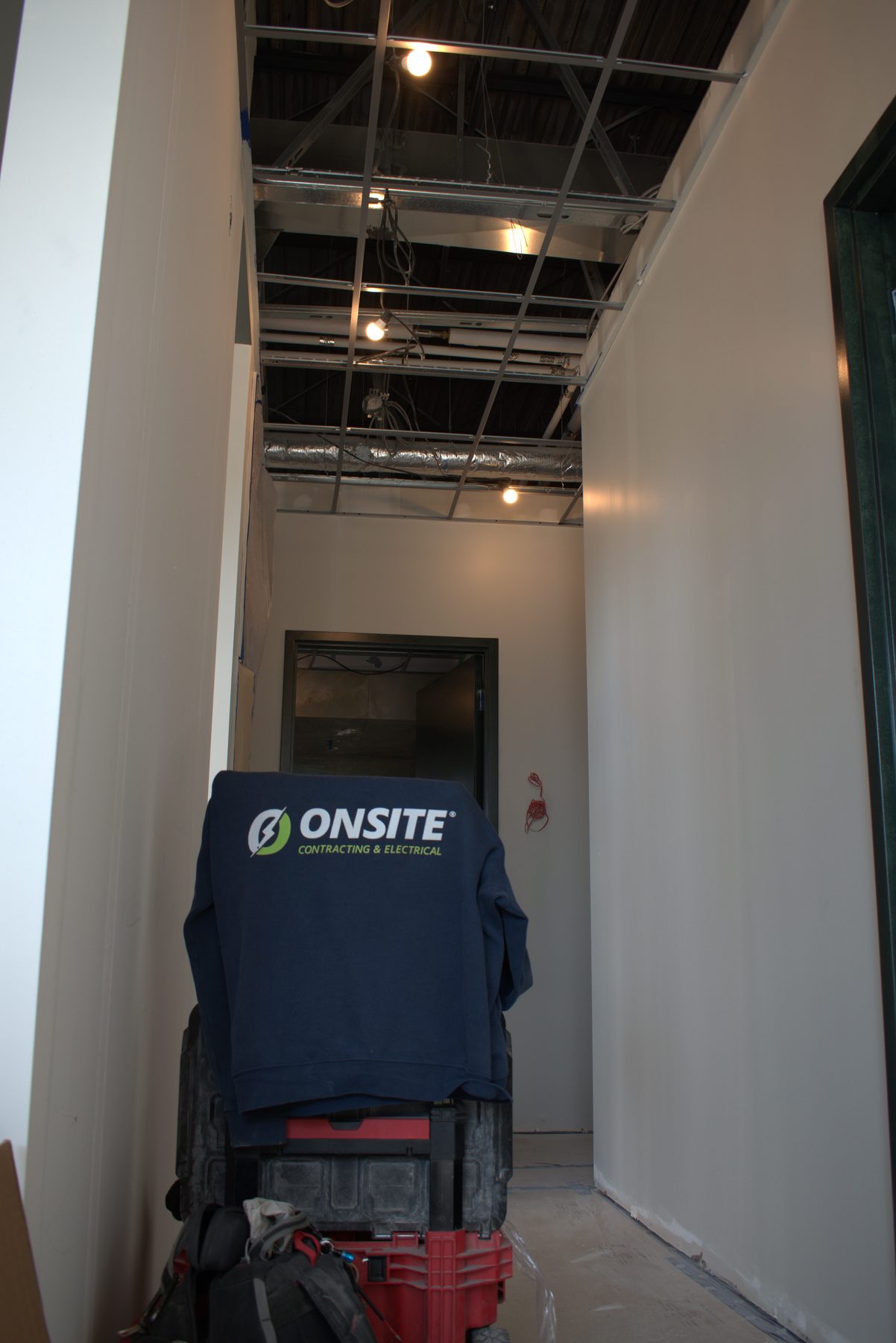 Hallway under construction with exposed ceiling, lights, and wiring — ONE8T (West District)