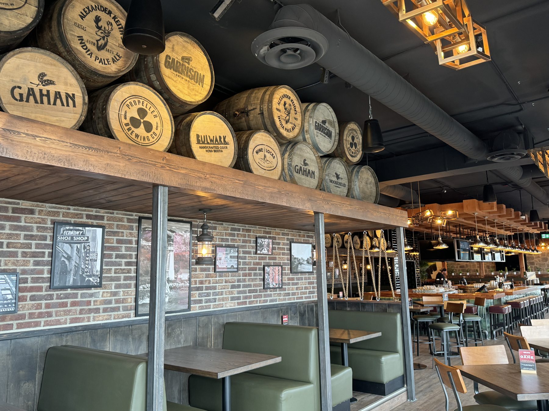 Wooden barrels displayed above green booths and brick walls — Blowers and Grafton (Shawnessy)