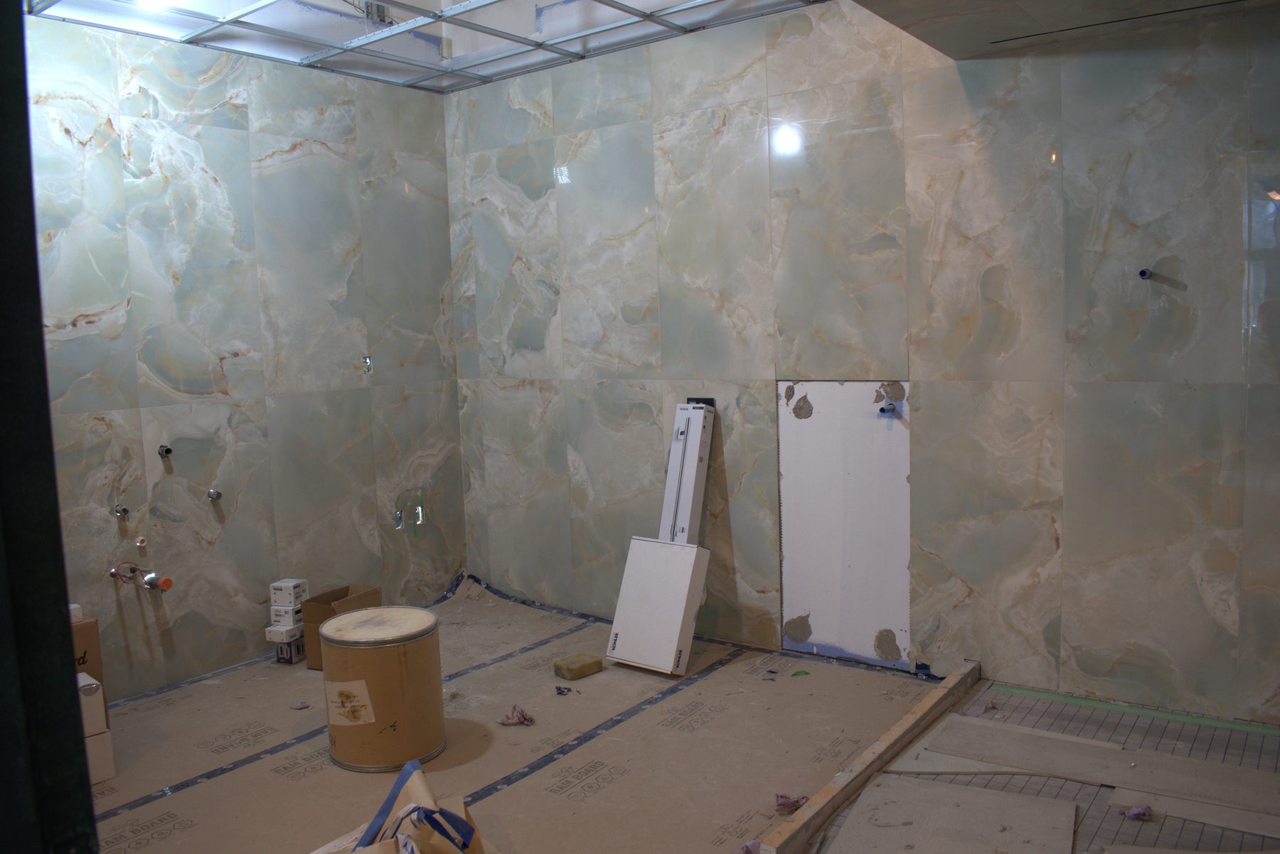 Bathroom renovation with marbled tile, in-wall fixtures, and construction materials — ONE8T (West District)