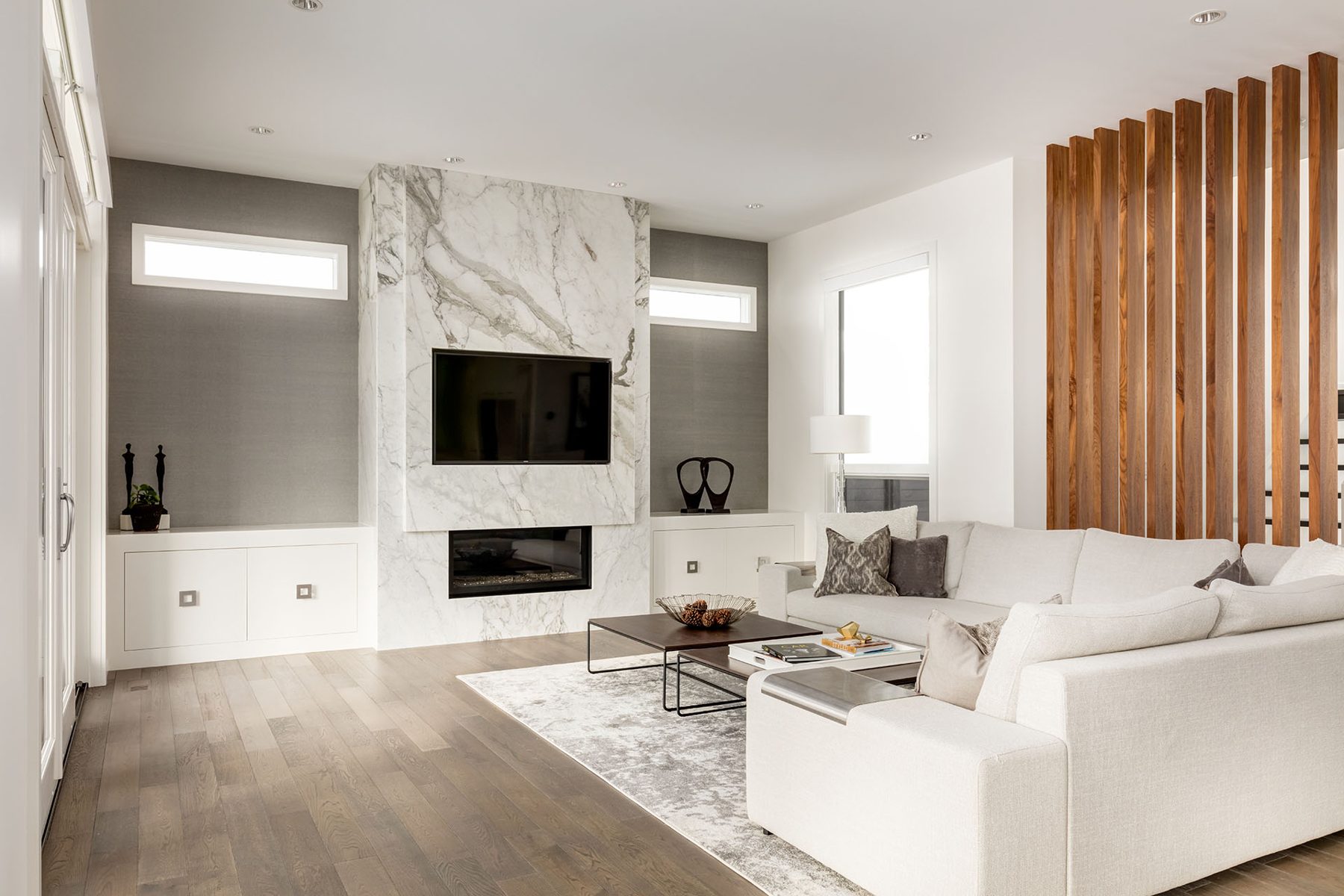 Modern living room with marble fireplace, sectional sofa, and wood slat accent wall — Casa Blanca