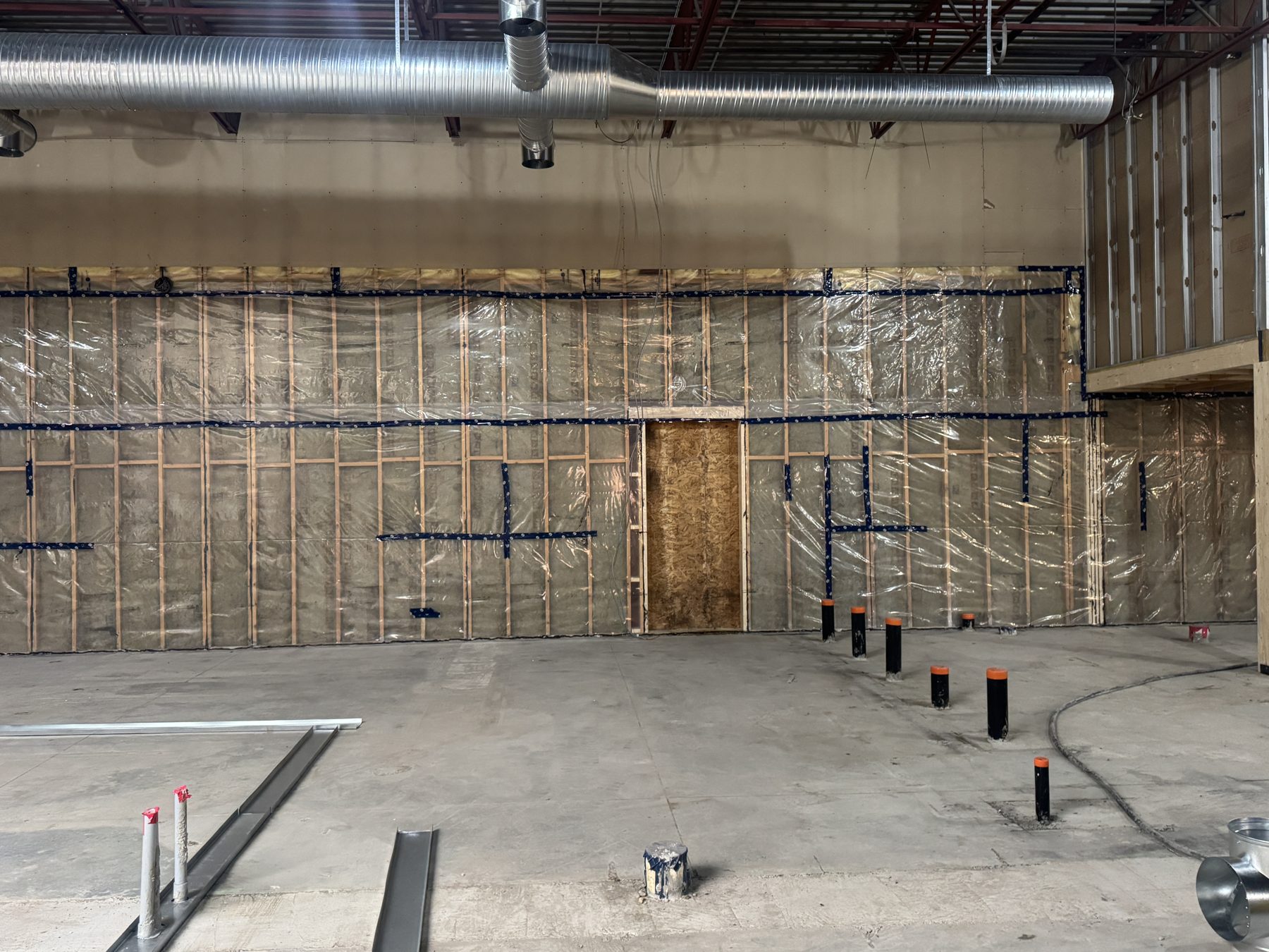 Insulated walls with plastic sheeting, plumbing pipes, and metal framing elements — Blowers and Grafton (Red Deer) by Onsite Contracting Services