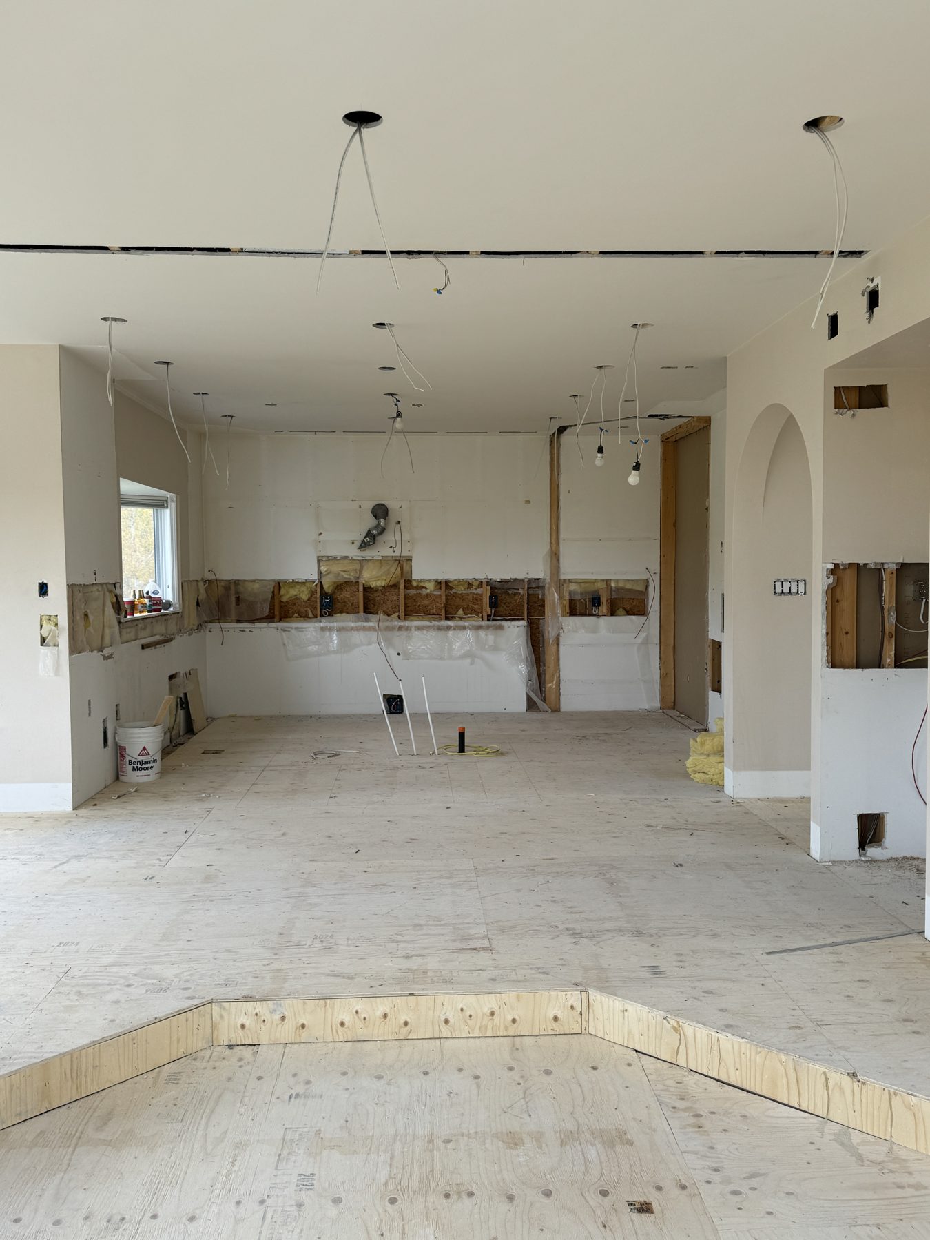 Kitchen under renovation, exposed wiring, plywood subfloor, open cabinets — 14 Lochend Drive, Cochrane