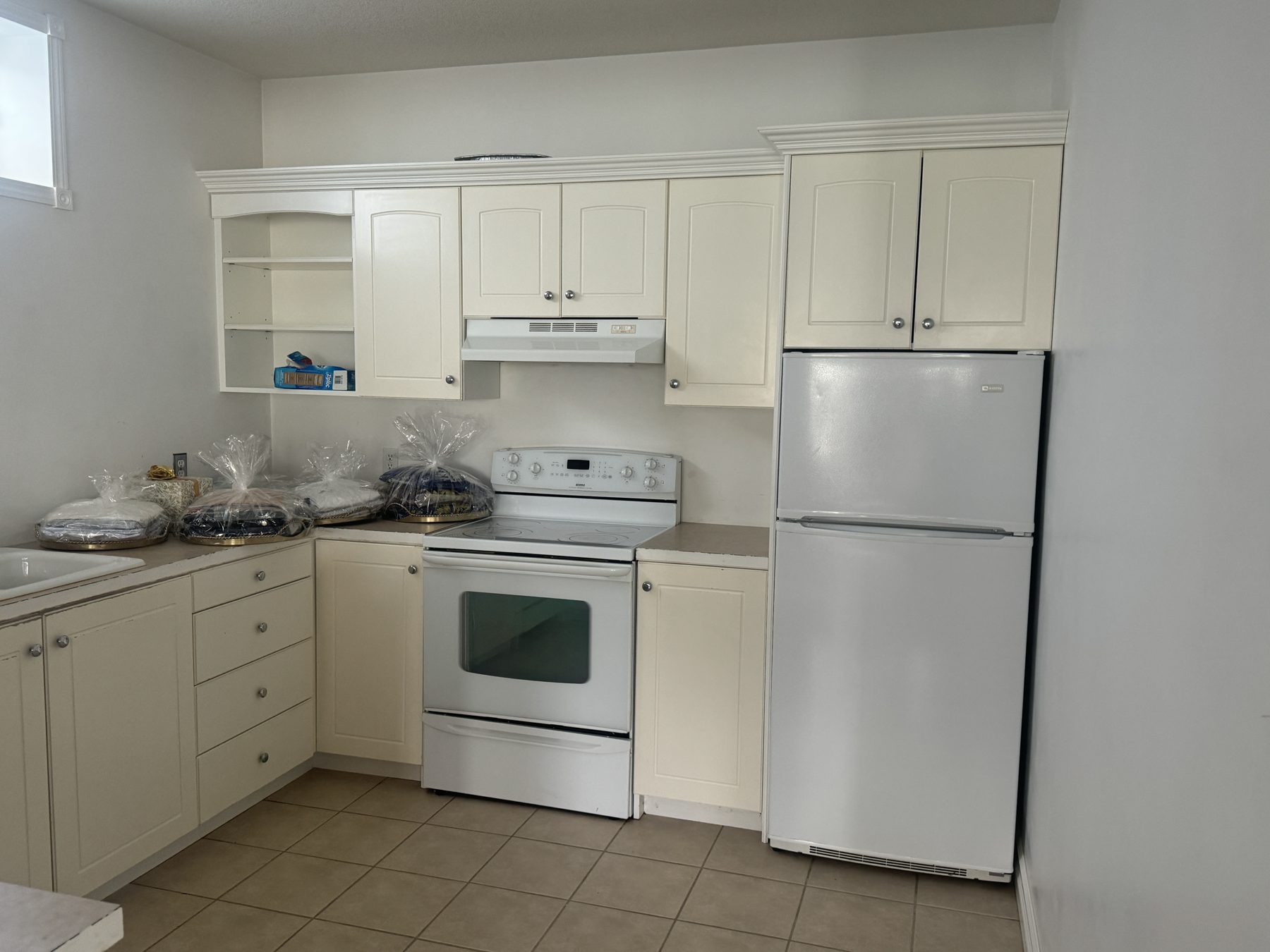 Kitchen with cream cabinets, white appliances, and new flooring — 14 Lochend Drive, Cochrane