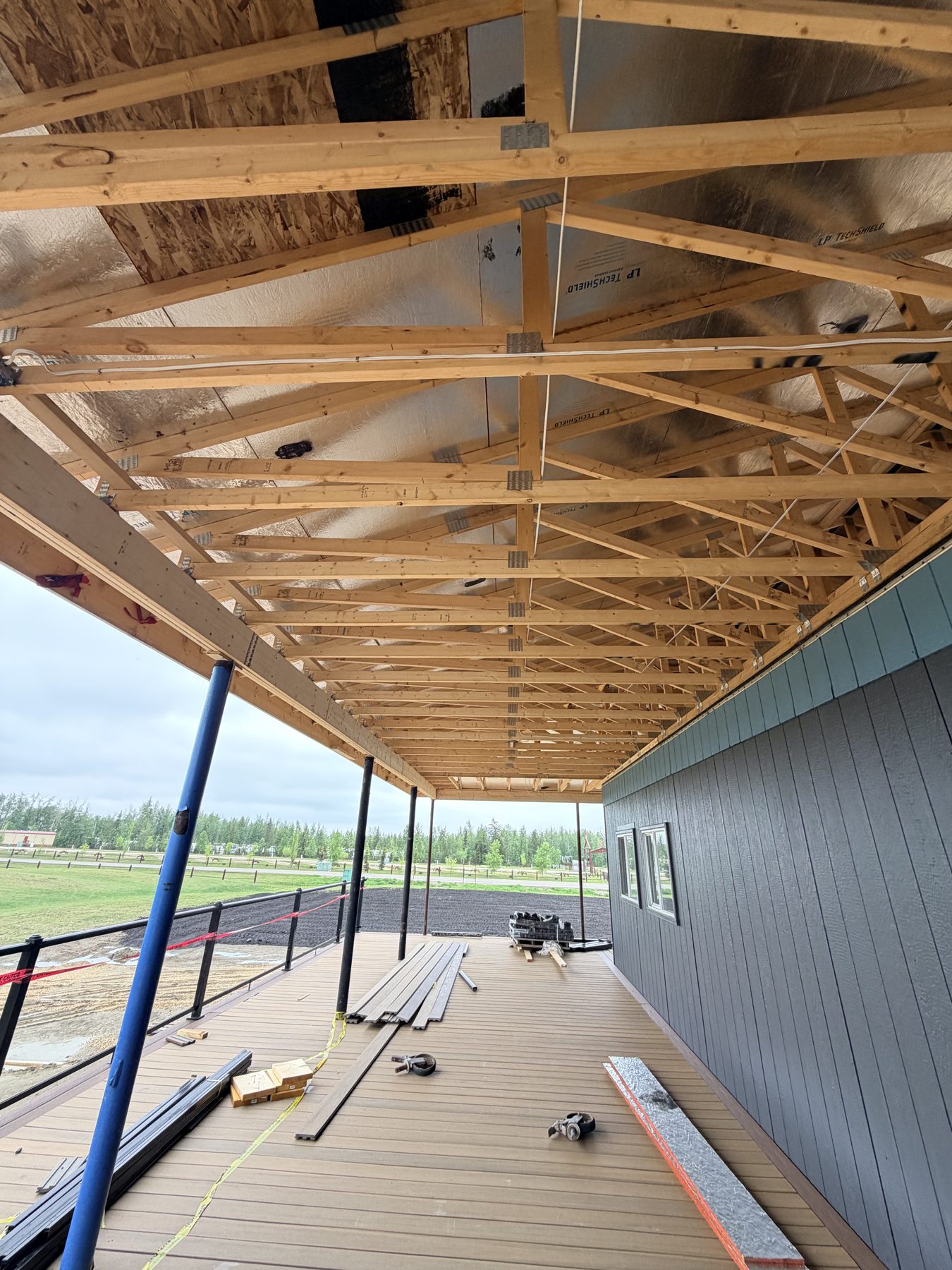 Wooden roof trusses and deck under construction with building materials staged — Sandy Point (Club House)