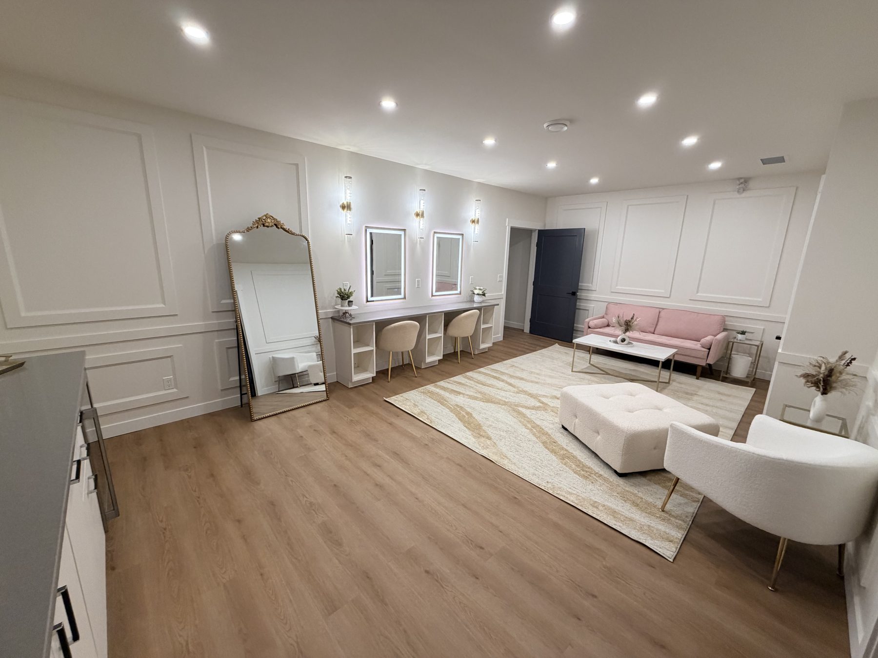 Renovated dressing room with vanity mirrors, pink sofa, and decorative moldings — The Barron Venue