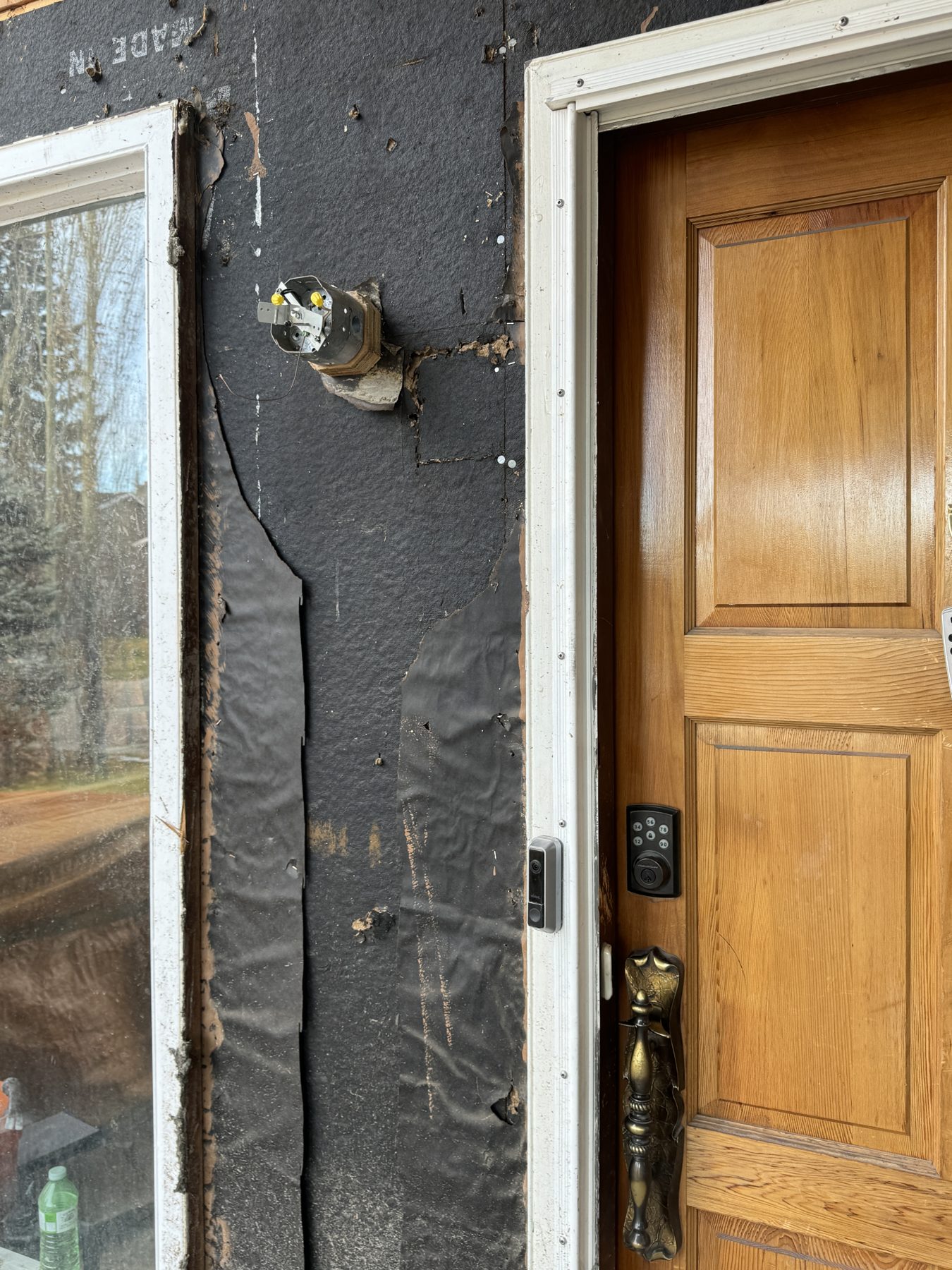 Exterior wall under renovation with detached sheathing and open electrical box — 188 Lake Adams Crescent SE, Calgary
