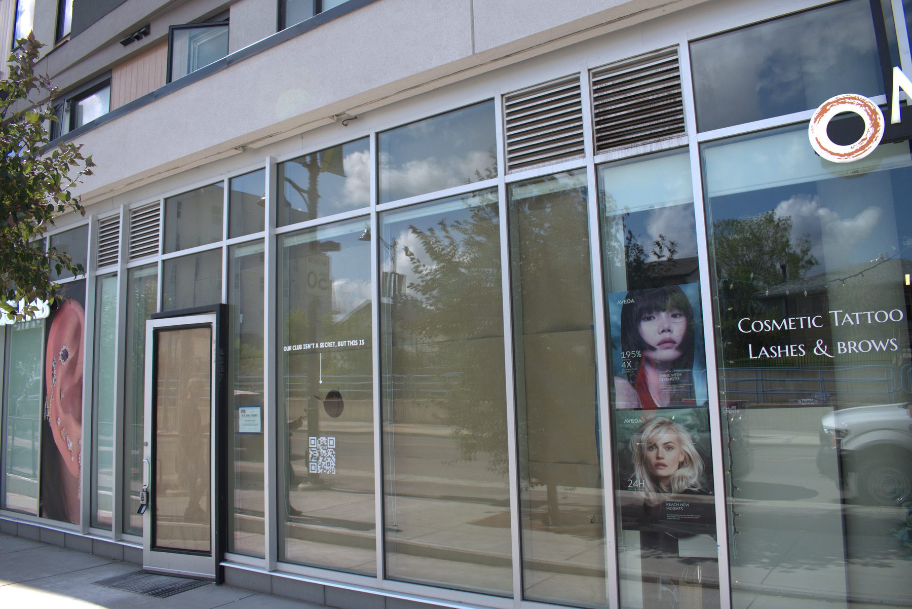 Storefront windows display salon advertisements and signage — Big Buns (Bowness)