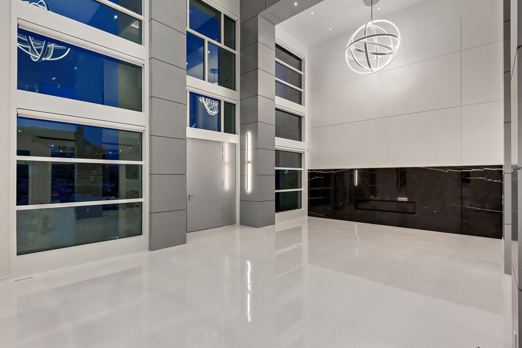 Modern entryway with large windows, white floors, and black marble wall — Blanc de Blanc
