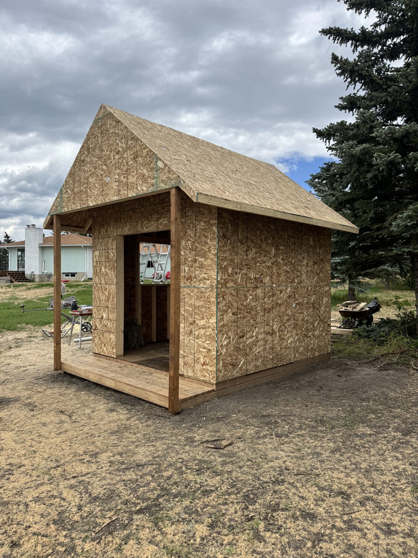 Shed under construction with OSB walls and roof, and wooden porch — 101 Lariat Loop, Calgary