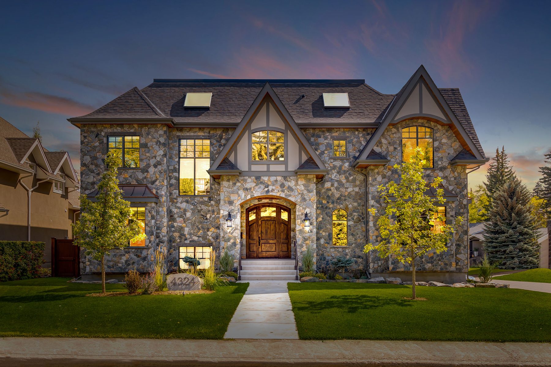 Exterior of large stone house with arched wooden doors and lit windows — Oxford