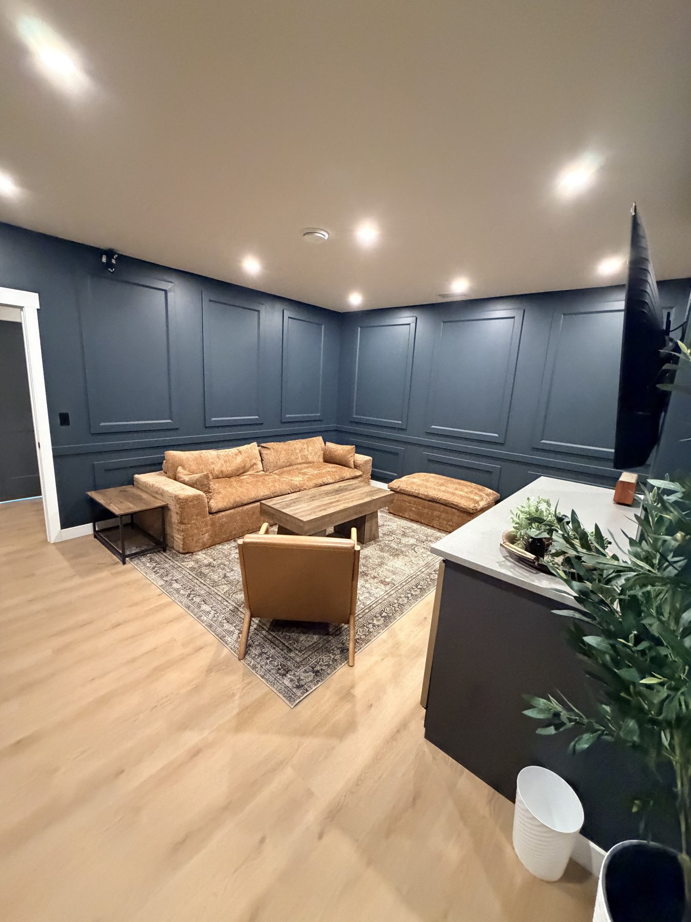 Living room with paneled walls, new flooring, couch, chairs, and ottoman — The Barron Venue