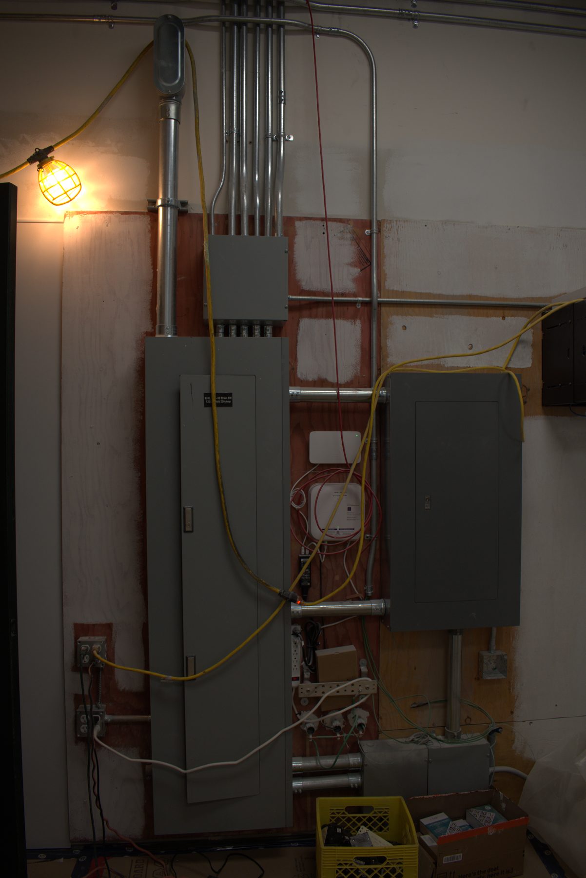 Electrical panel installation with conduit, wiring, and temporary lighting — ONE8T (West District)