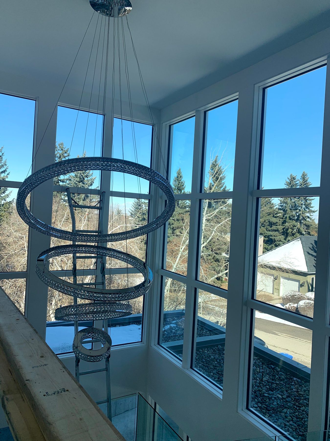 Modern multi-tiered crystal chandelier installation in a bright, tall space — Pump Hill