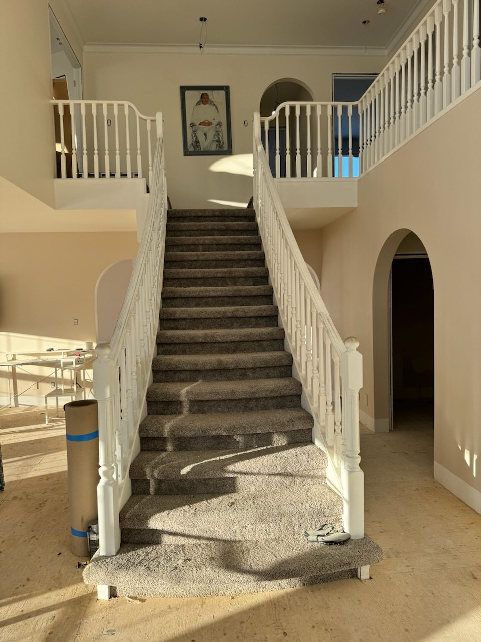 Carpeted stairs and balustrades in a room under renovation — 14 Lochend Drive, Cochrane