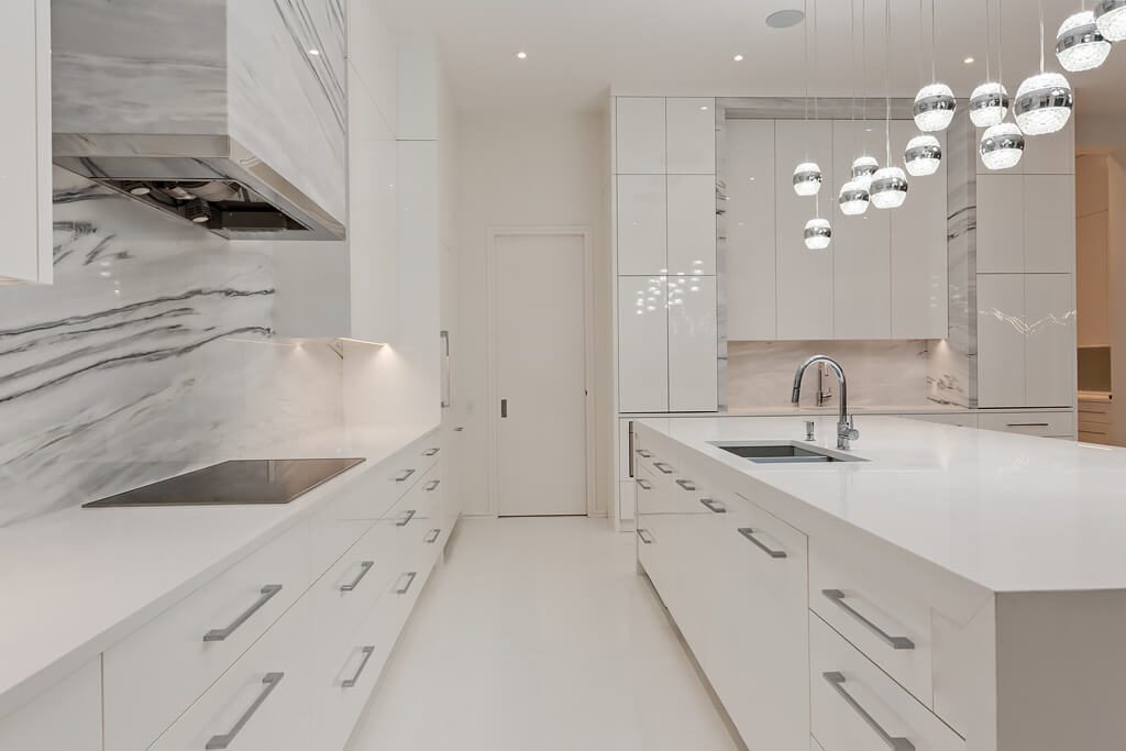 Modern white kitchen with marble backsplash, island, and pendant lights — Blanc de Blanc