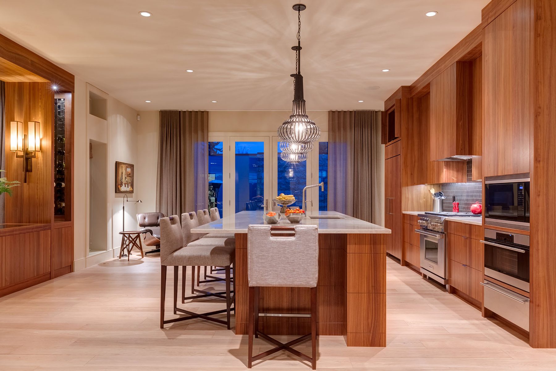 Modern kitchen with wooden cabinets, marble island, and bar stools — Evolution