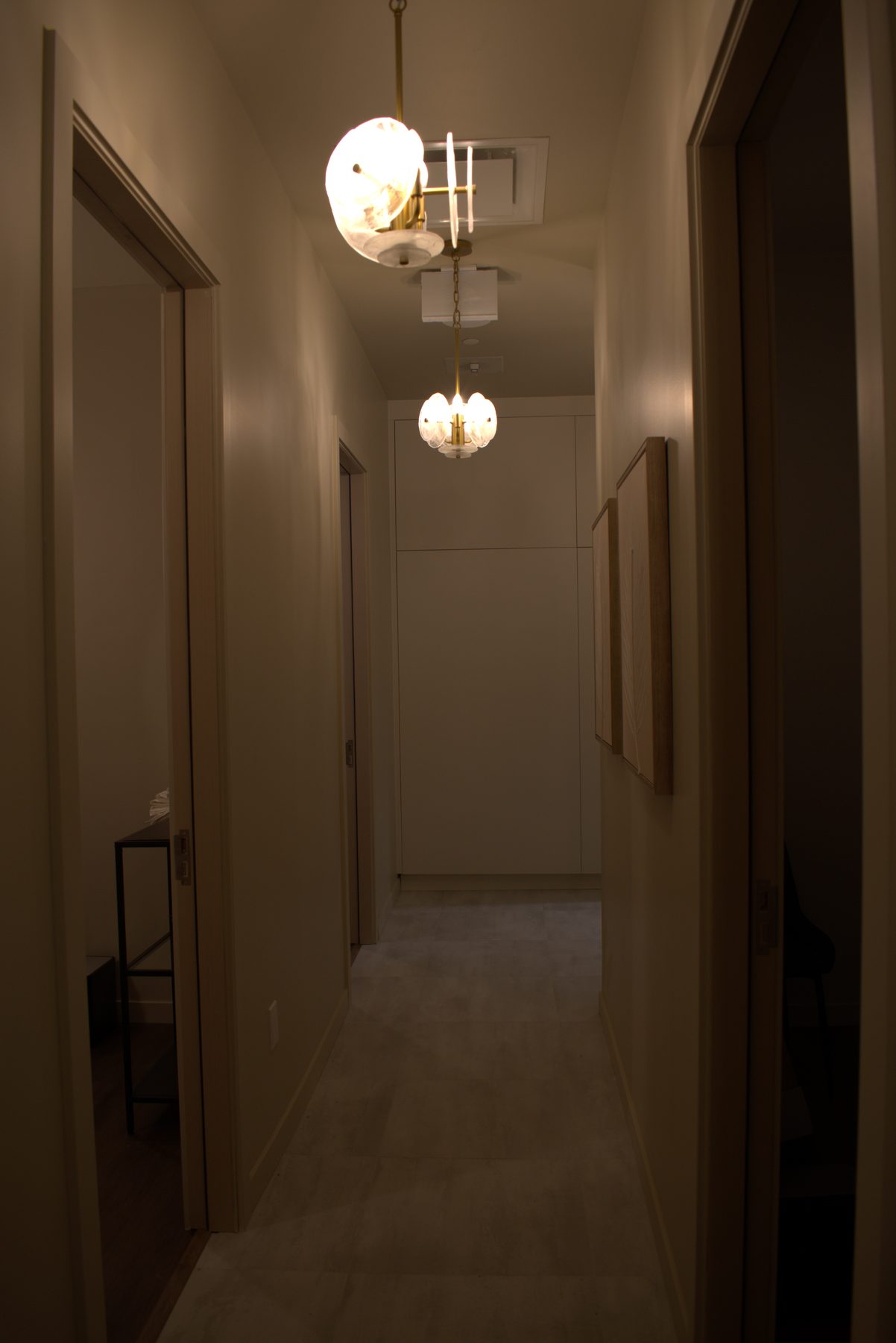 Hallway with pendant lights, neutral walls, and wood-framed art — Leela Spa (Bankers Hall)