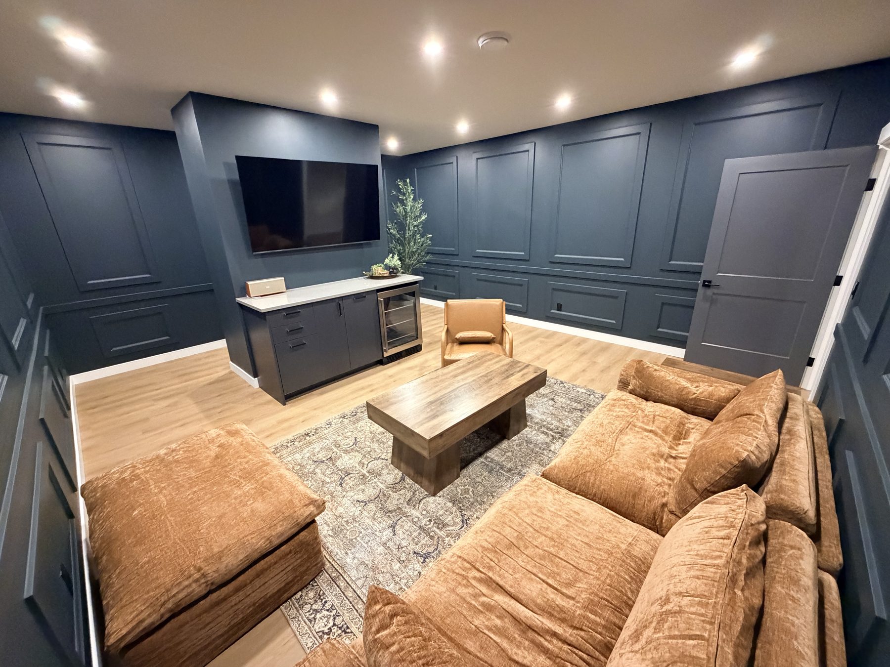 Living room with wainscoted walls, entertainment center, and plush seating — The Barron Venue