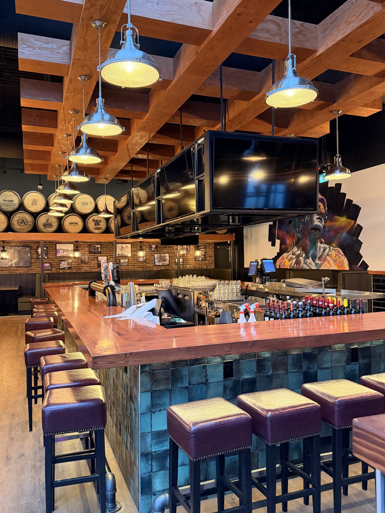 Bar with wood ceiling beams, pendant lights, and row of stools — Blowers and Grafton (Red Deer)