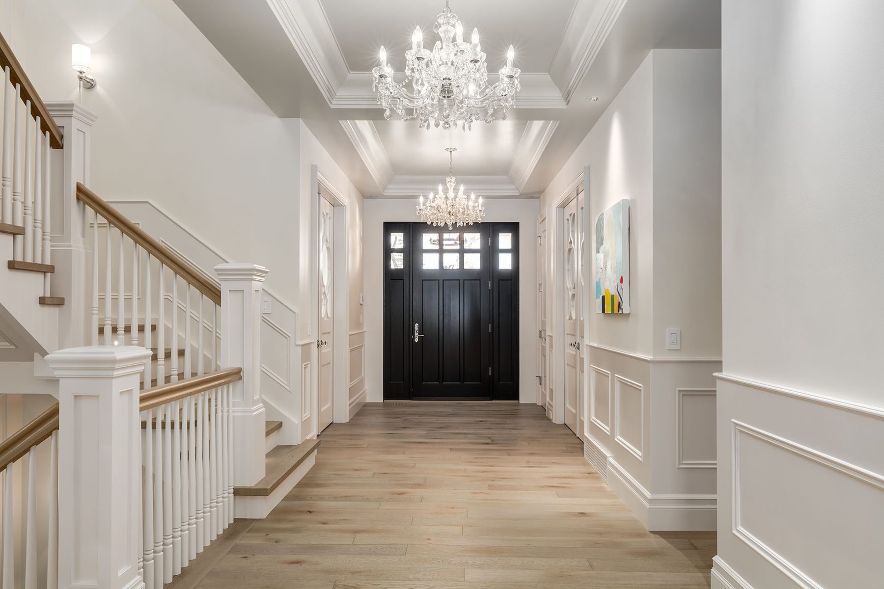 Modern foyer with double chandeliers, wainscoting, and wood floors — White House