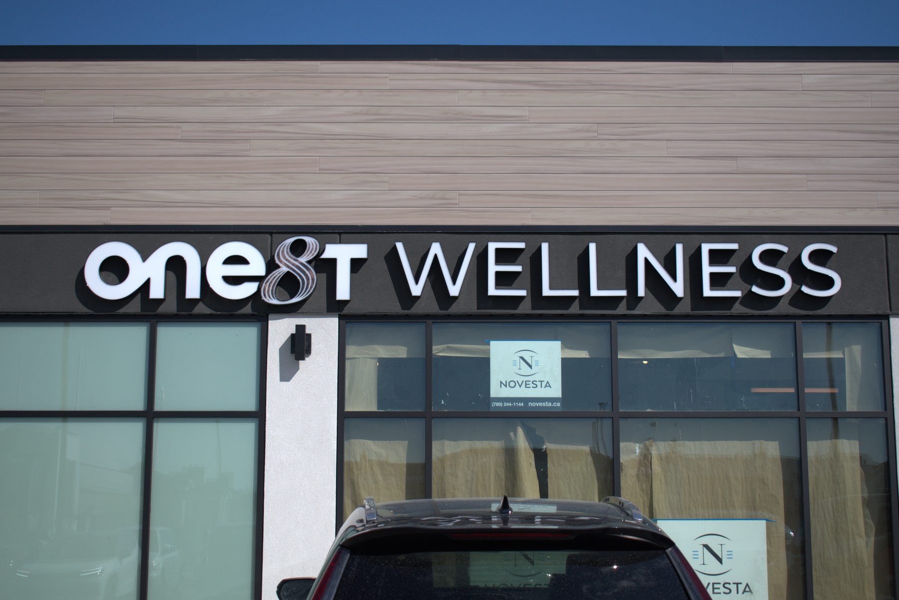 Exterior signage installed on a building with wood-like siding — ONE8T (West District)