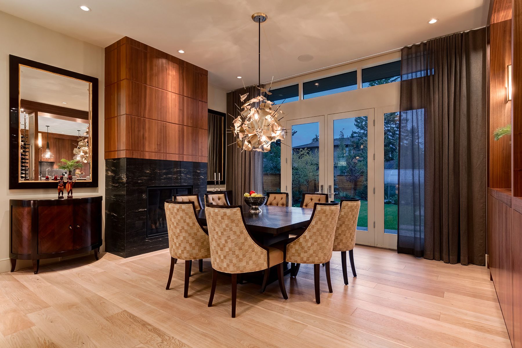 Dining room with wood fireplace, dark granite hearth, and upholstered chairs — Evolution