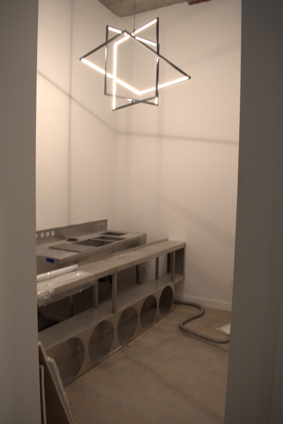 Unfinished room with stainless steel counters and a geometric chandelier — Big Buns (Bowness)