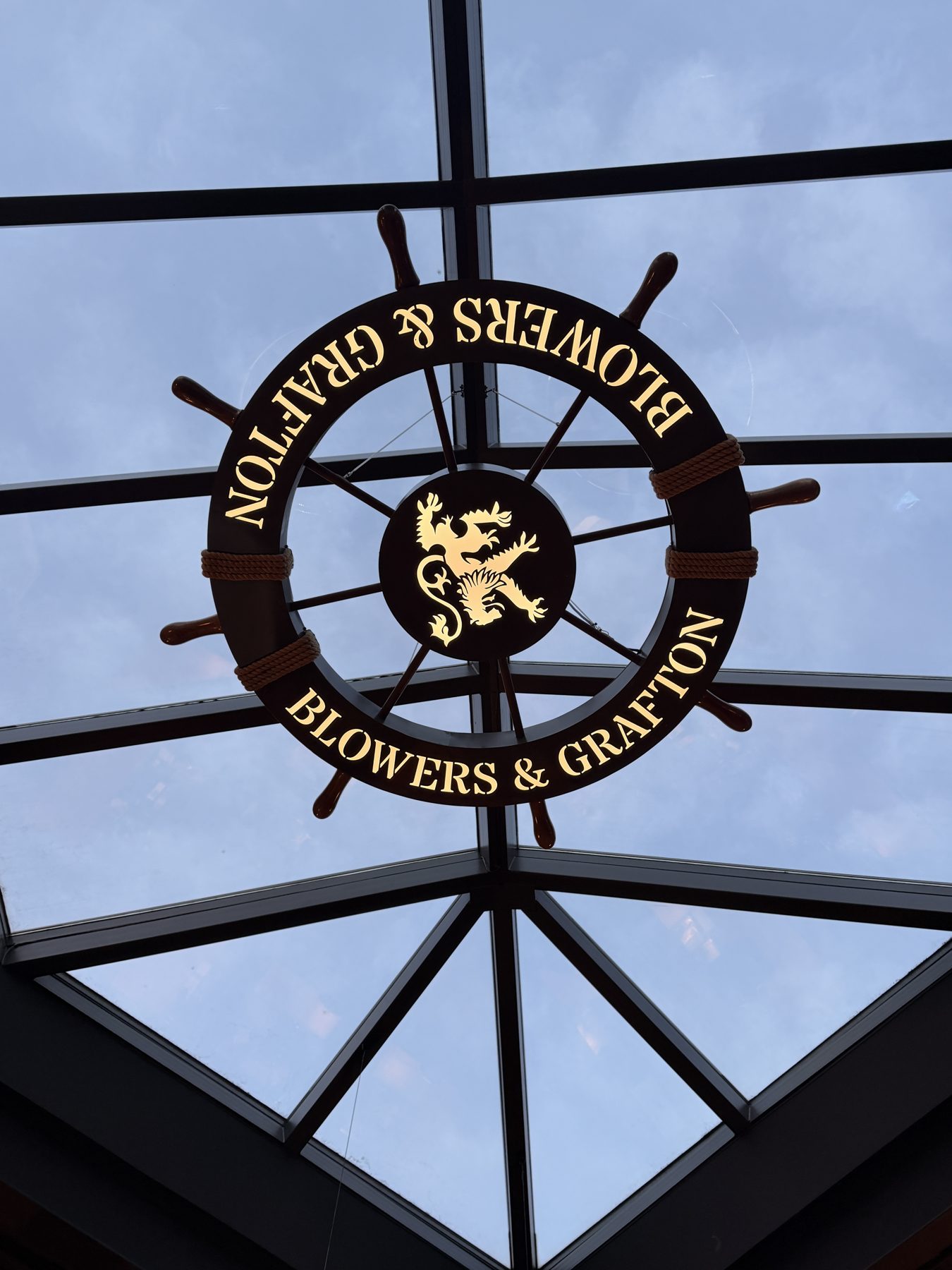 Ship's wheel sign with text and lion crest above skylight — Blowers and Grafton (Red Deer)