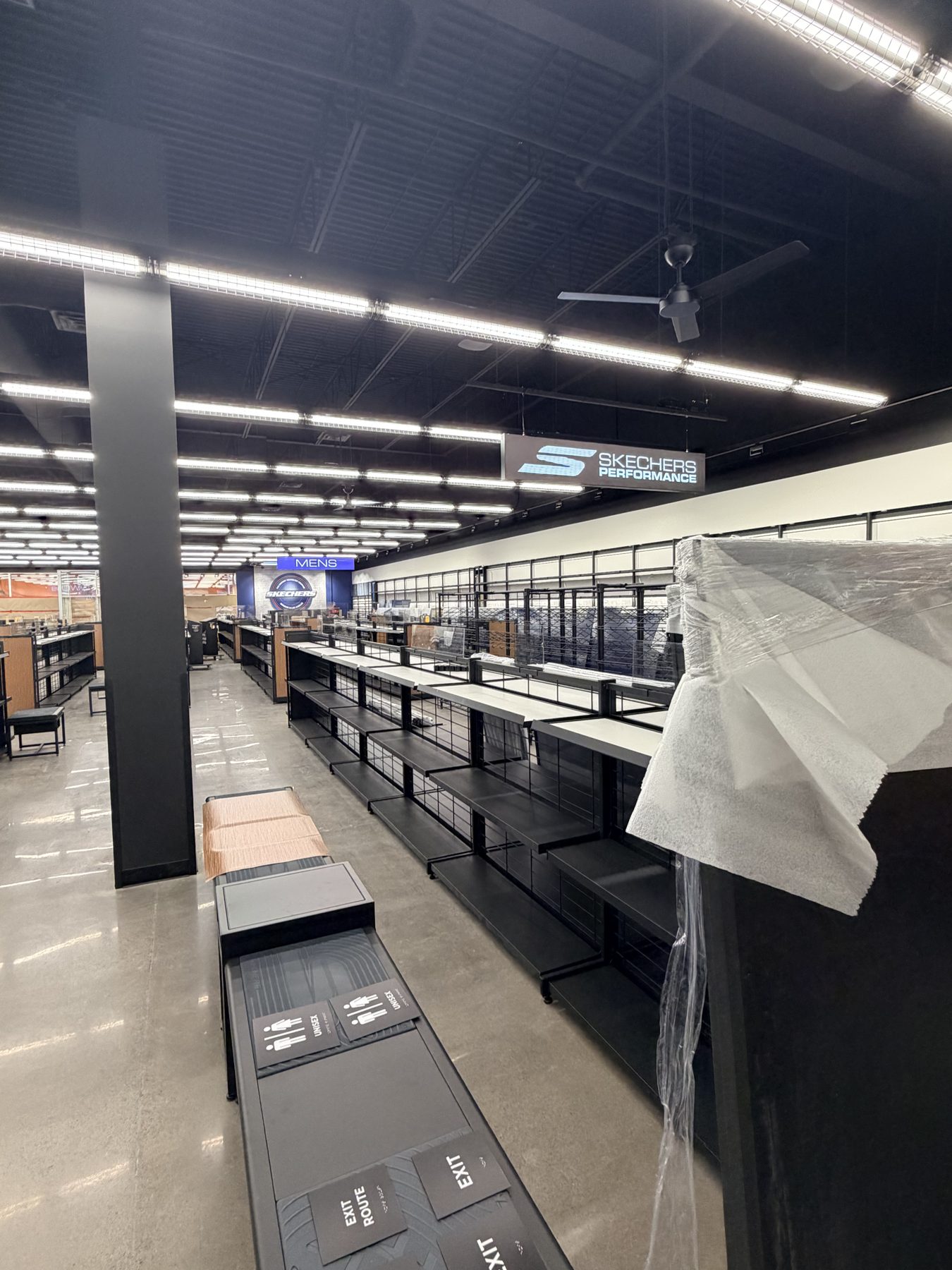 Retail store under renovation with empty shelves and new fixtures visible — Skechers (Signal Hill)