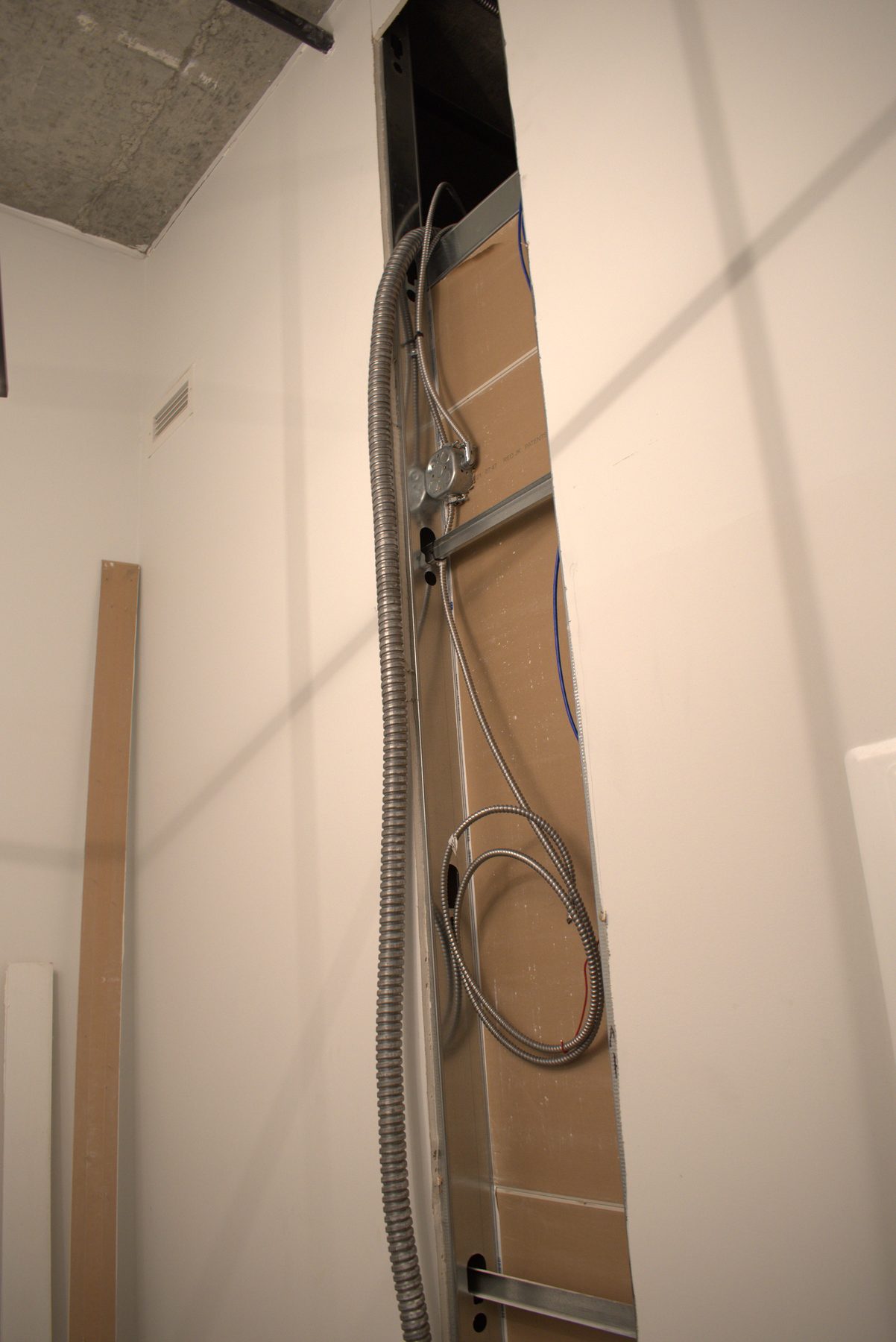 Exposed electrical conduit, junction box, and wires inside wall opening — Big Buns (Bowness)