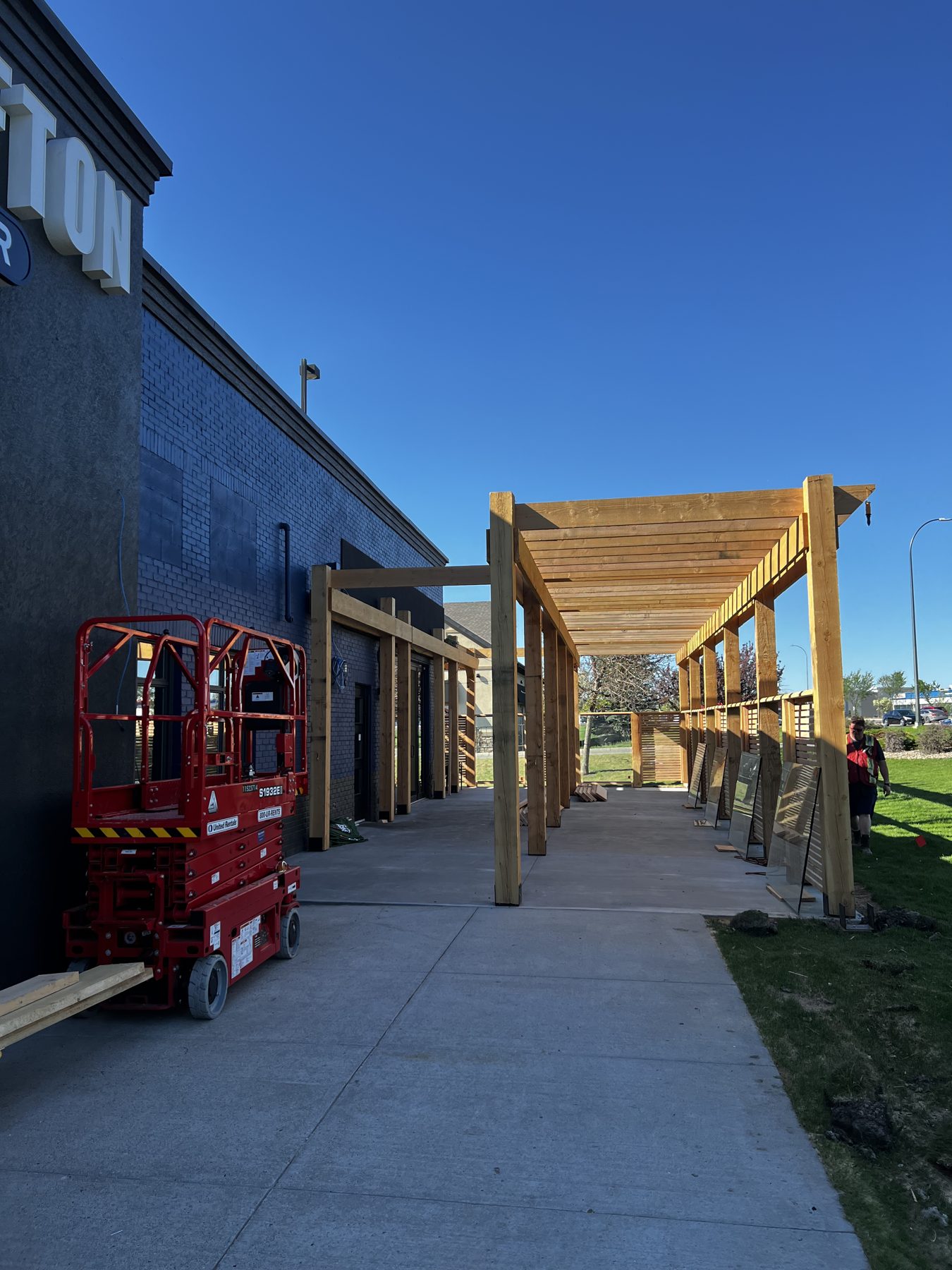 Building exterior with new wooden pergola construction and red lift — Blowers and Grafton (Lethbridge)