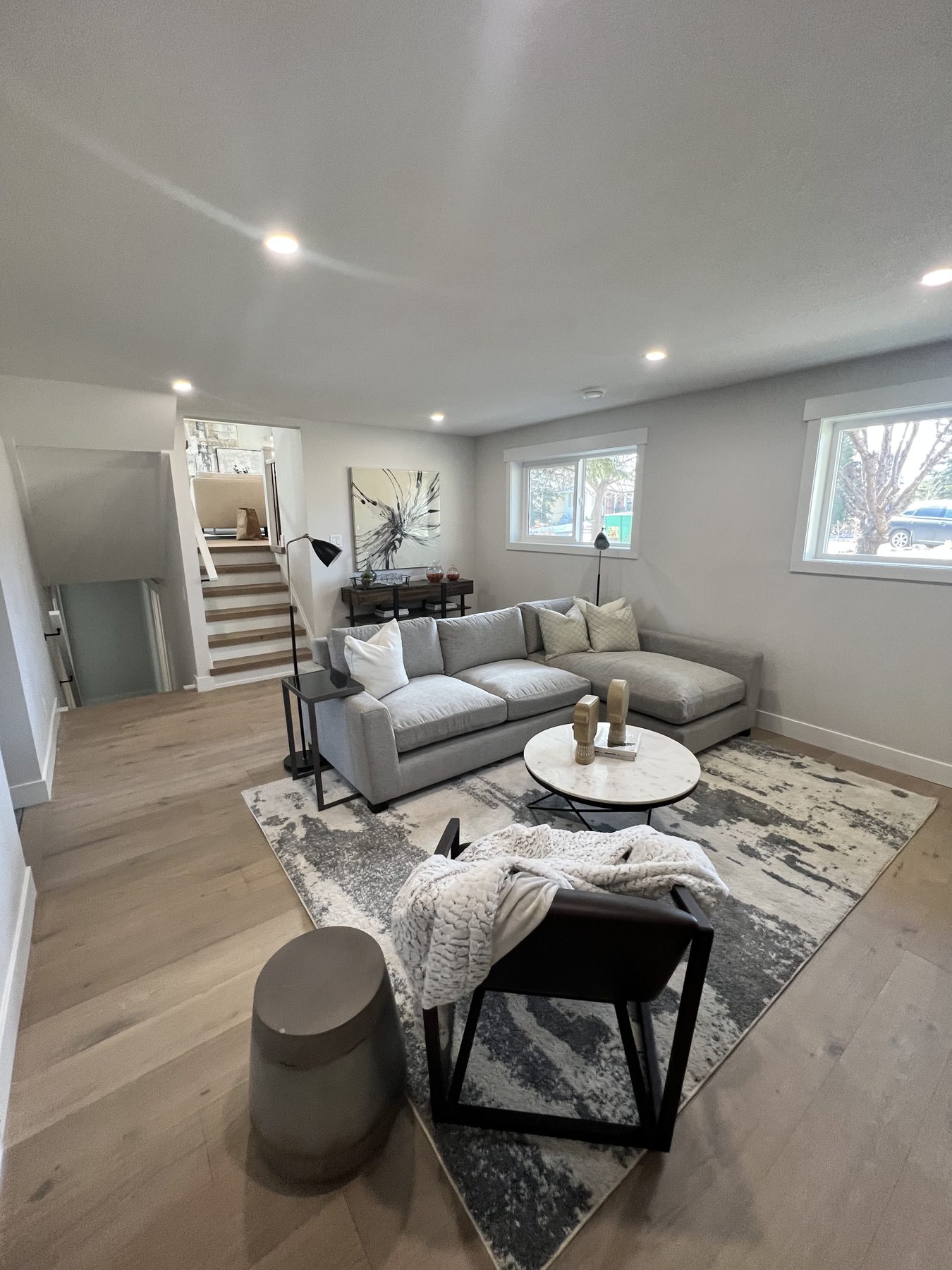 Newly renovated living room with gray sectional and modern decor — 720 Lake Twintree Crescent SE, Calgary