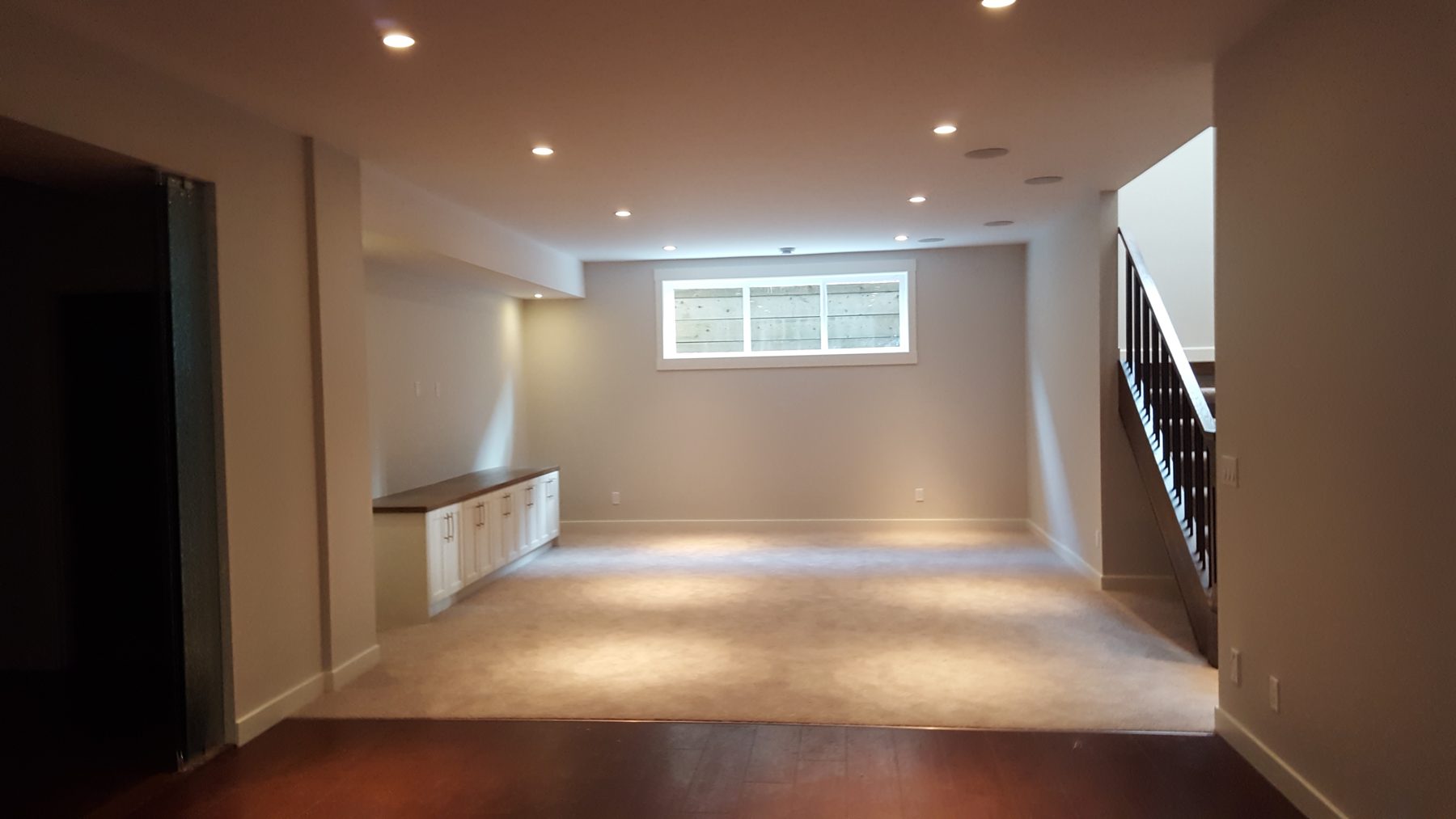 Newly carpeted basement with white cabinets and staircase nearing completion — Briar Hill